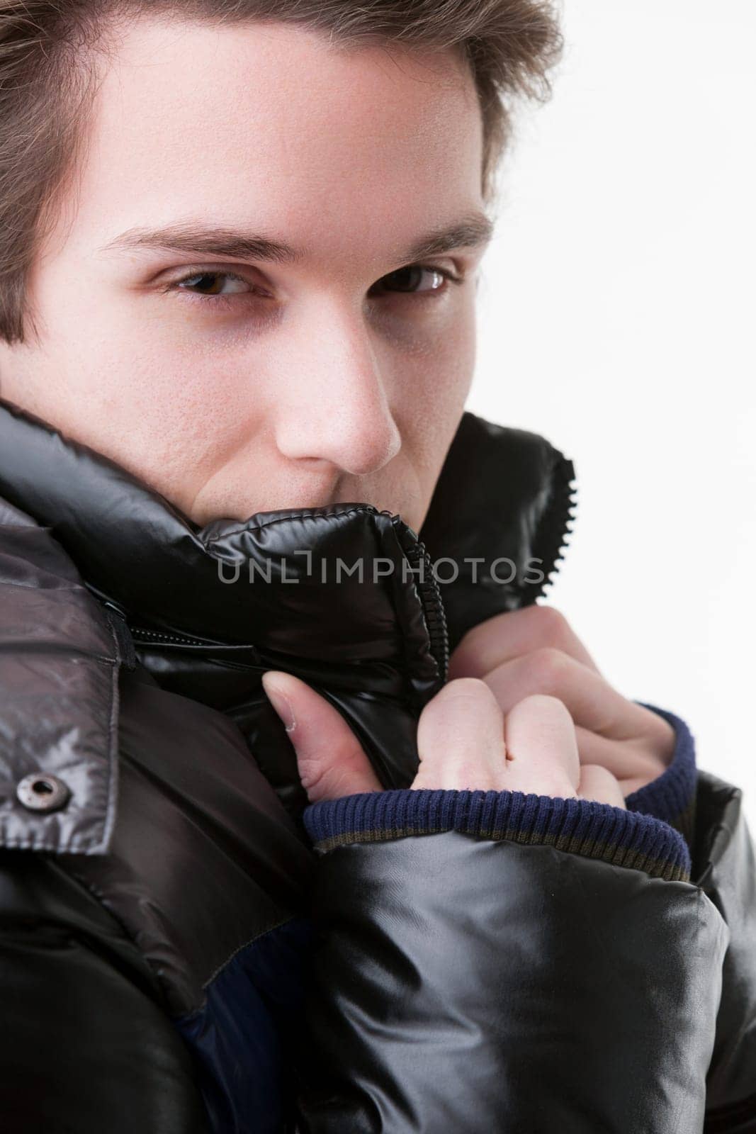 With a dark, charismatic stare, a young man adjusts the collar of his black down jacket, hiding everything but his eyes. It's a mix of winter trend and masculine charm