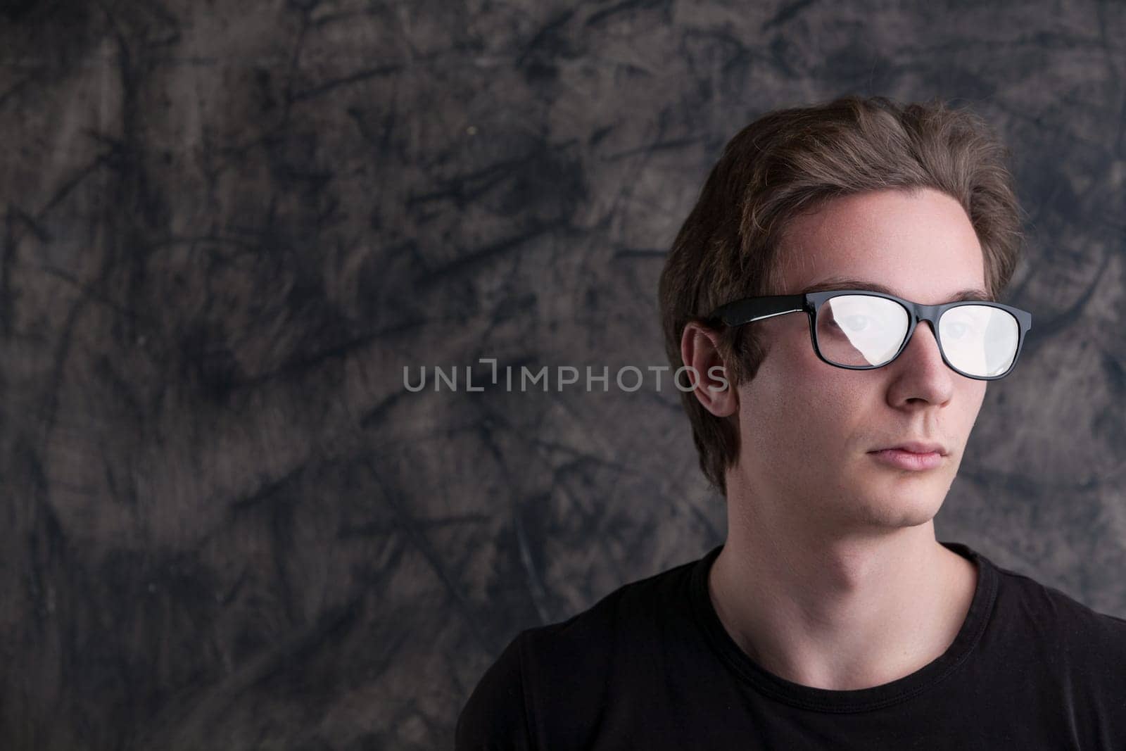 Mysterious reflections in his glasses, a light-brown-haired man stands against grunge. In a black shirt, he's absorbed in concerns for humanity's future amid tech discoveries