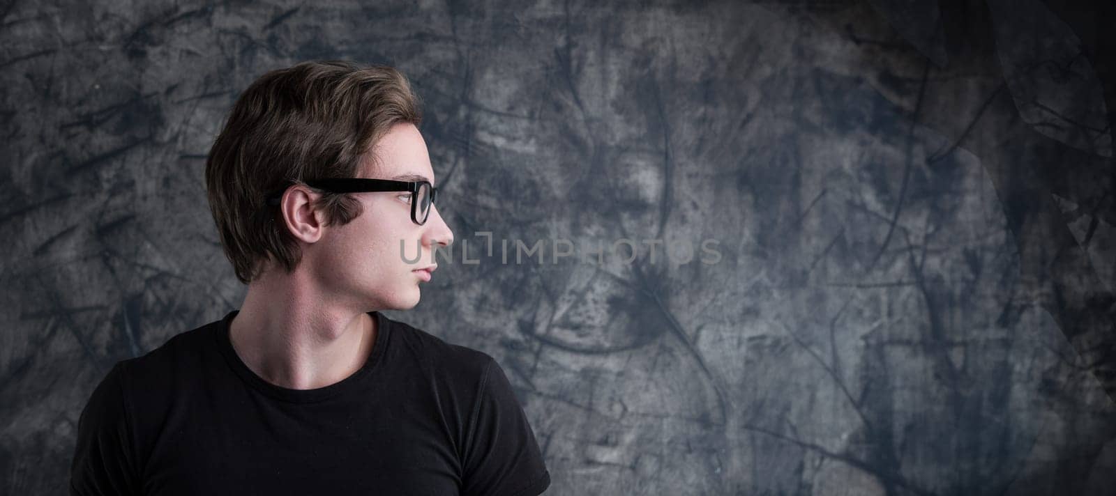 Pondering deeply, a young man with light-brown hair contrasts a grunge backdrop. His intense look creates a perfect COPYSPACE