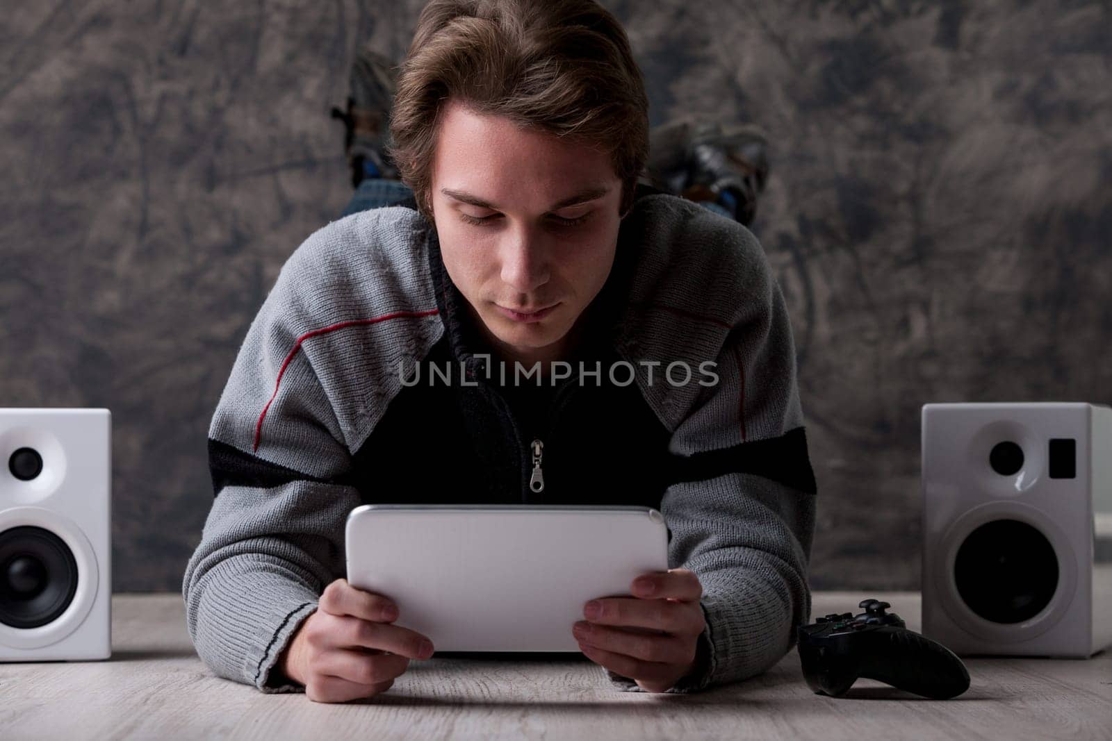 On the floor, a man with a tablet and gaming setup. With endless online content, there's no need for DVDs, CDs, or books anymore