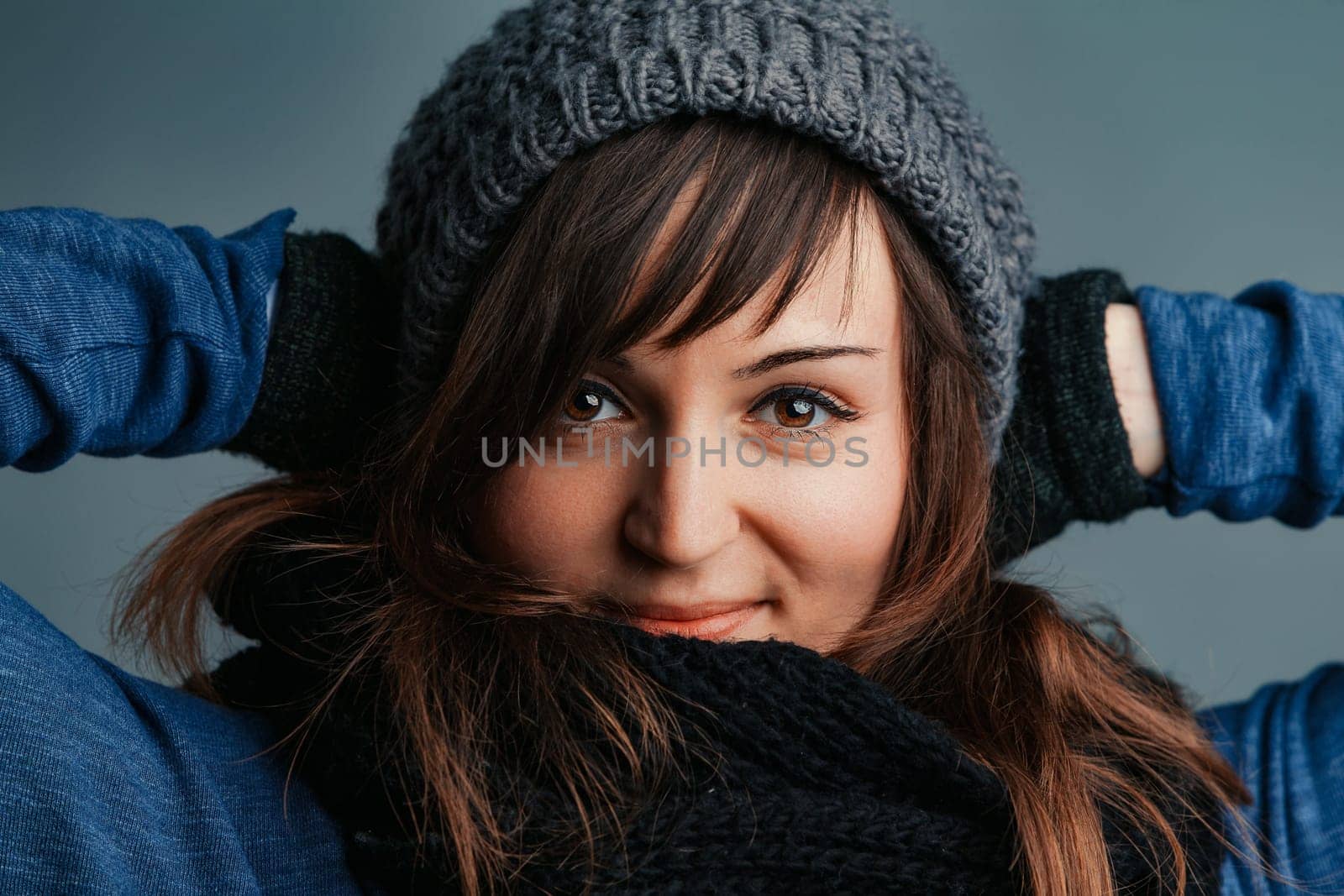Regardless of the chill, a woman with long brown hair and vibrant eyes enjoys her winter outfits: wool gloves, scarf, and cozy jumpers