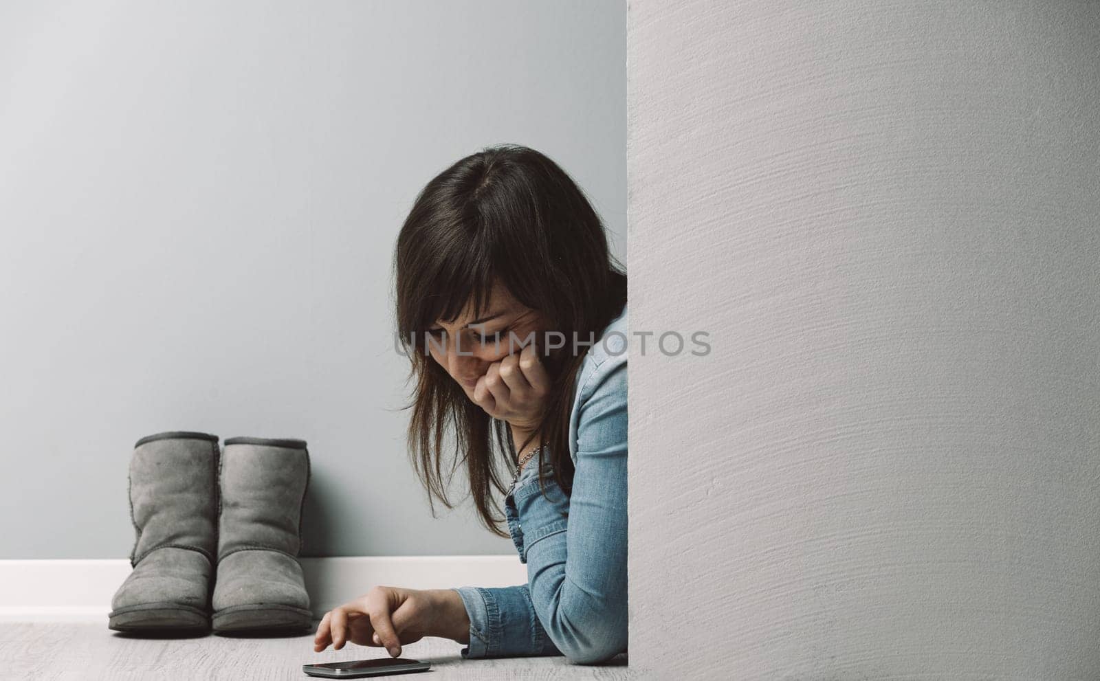 woman lies near winter boots, peeking from behind a COPYSPACE partition. She enjoys her smartphone and eco-friendly heating