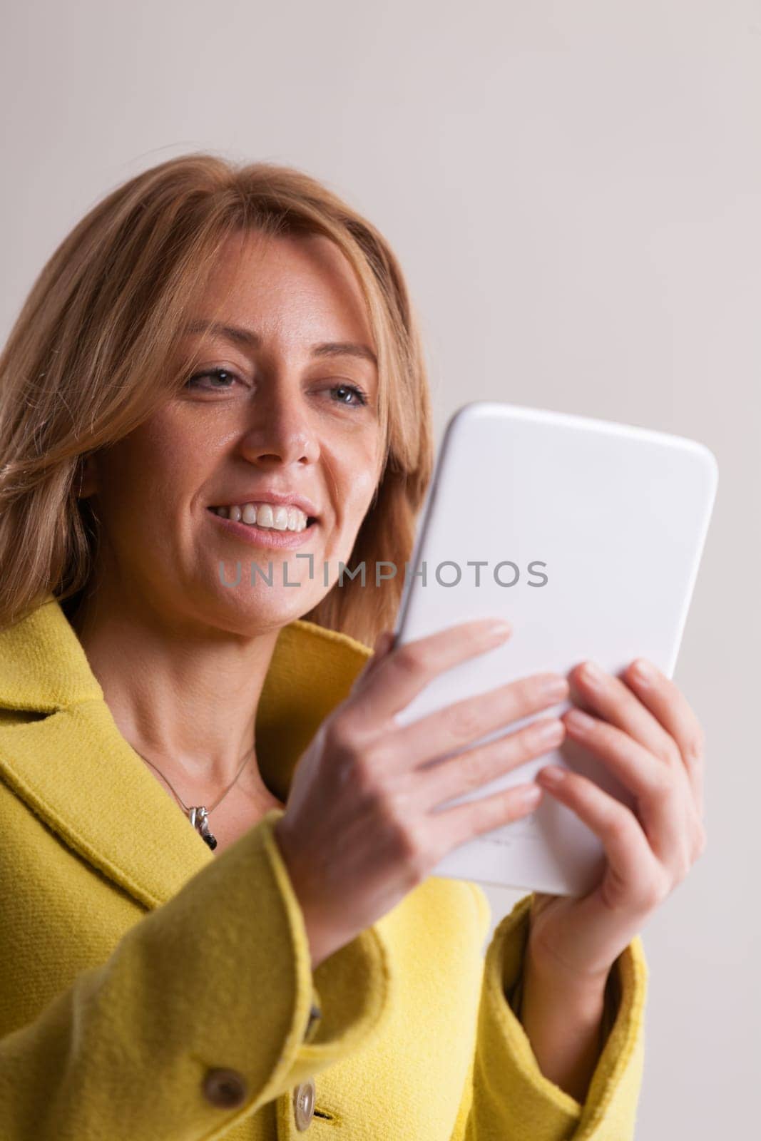 Woman in yellow navigates the vast digital ecosystem via her tablet. Seamlessly moving between professional duties, health, personal tasks, revelry, and the world of online dating