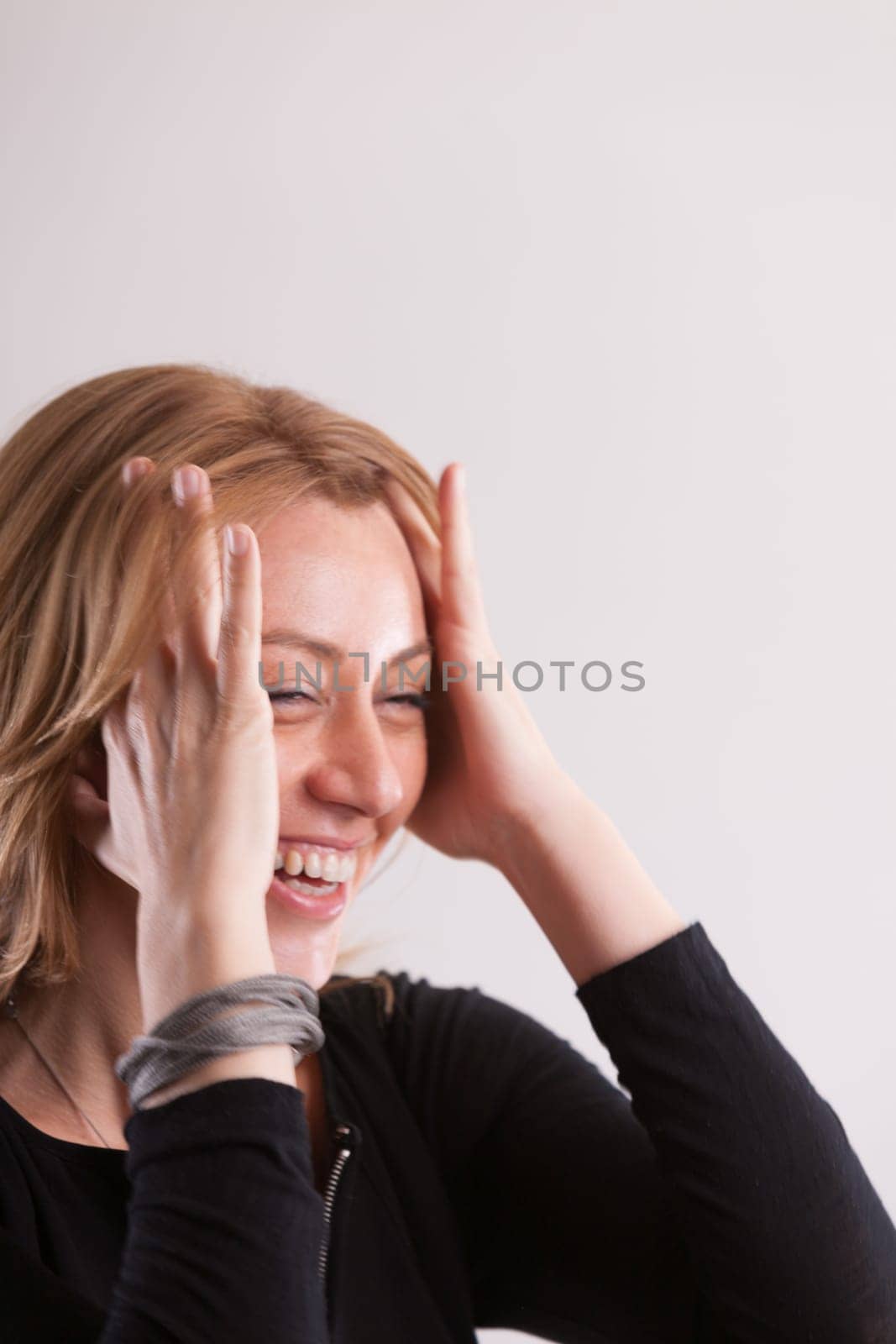 oyful close-up: a woman laughs, sweeping hair from her temples. The motion not just functional but perhaps underlining the hilarity of a comment. Pure positivity. Plenty of copyspace above