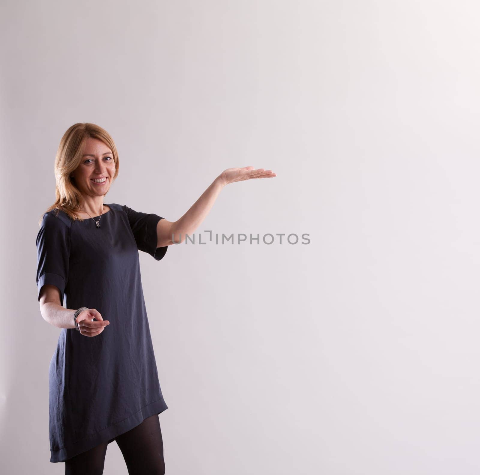 Dressed in blue, a woman suggests an unseen product (place yours here), smiling and gesturing towards you. She seems to assure you of its valuable attributes and advantages