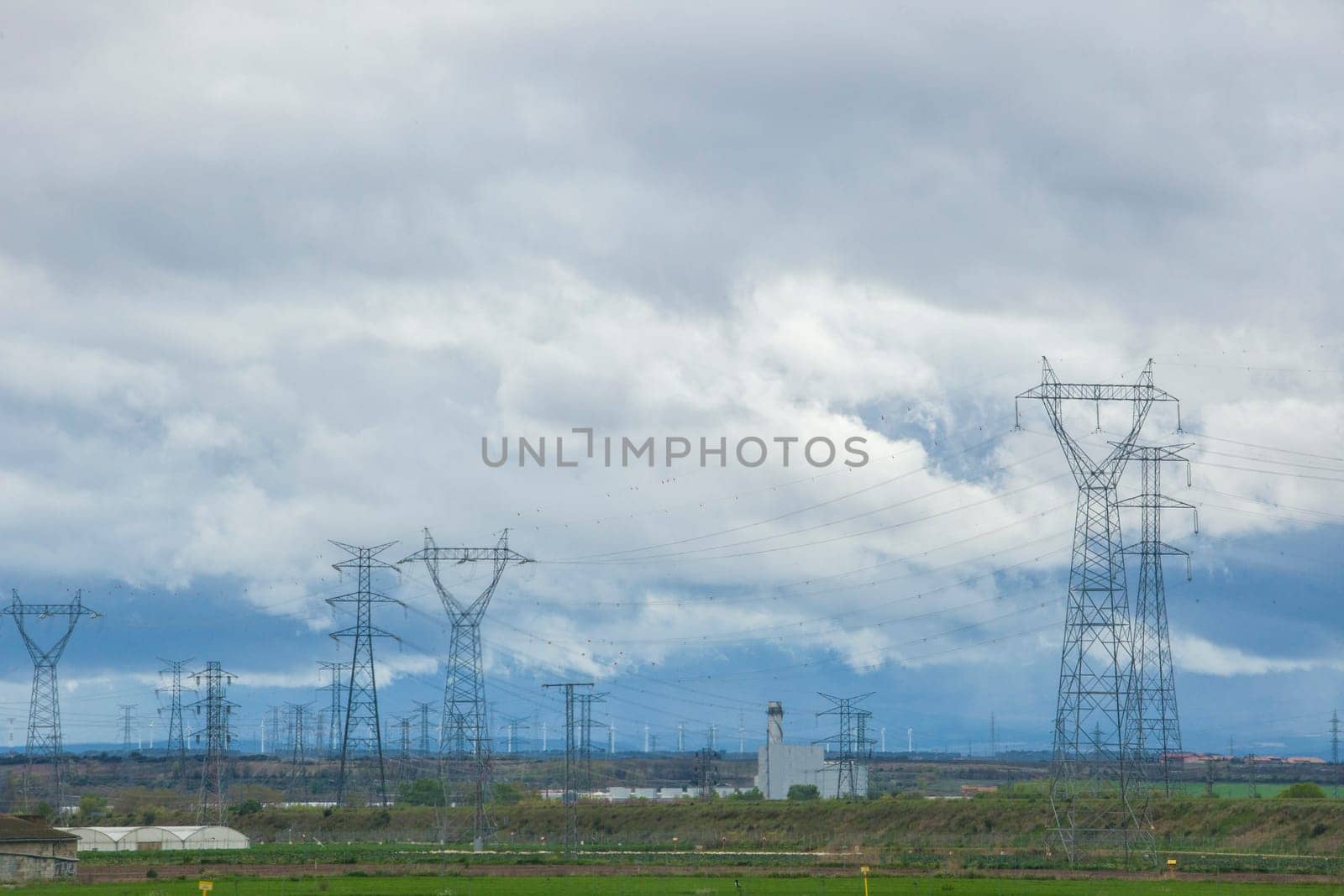Rural landscape hidden by electric towers, high voltage cables and wind turbines. Wind turbines environmental impact concept