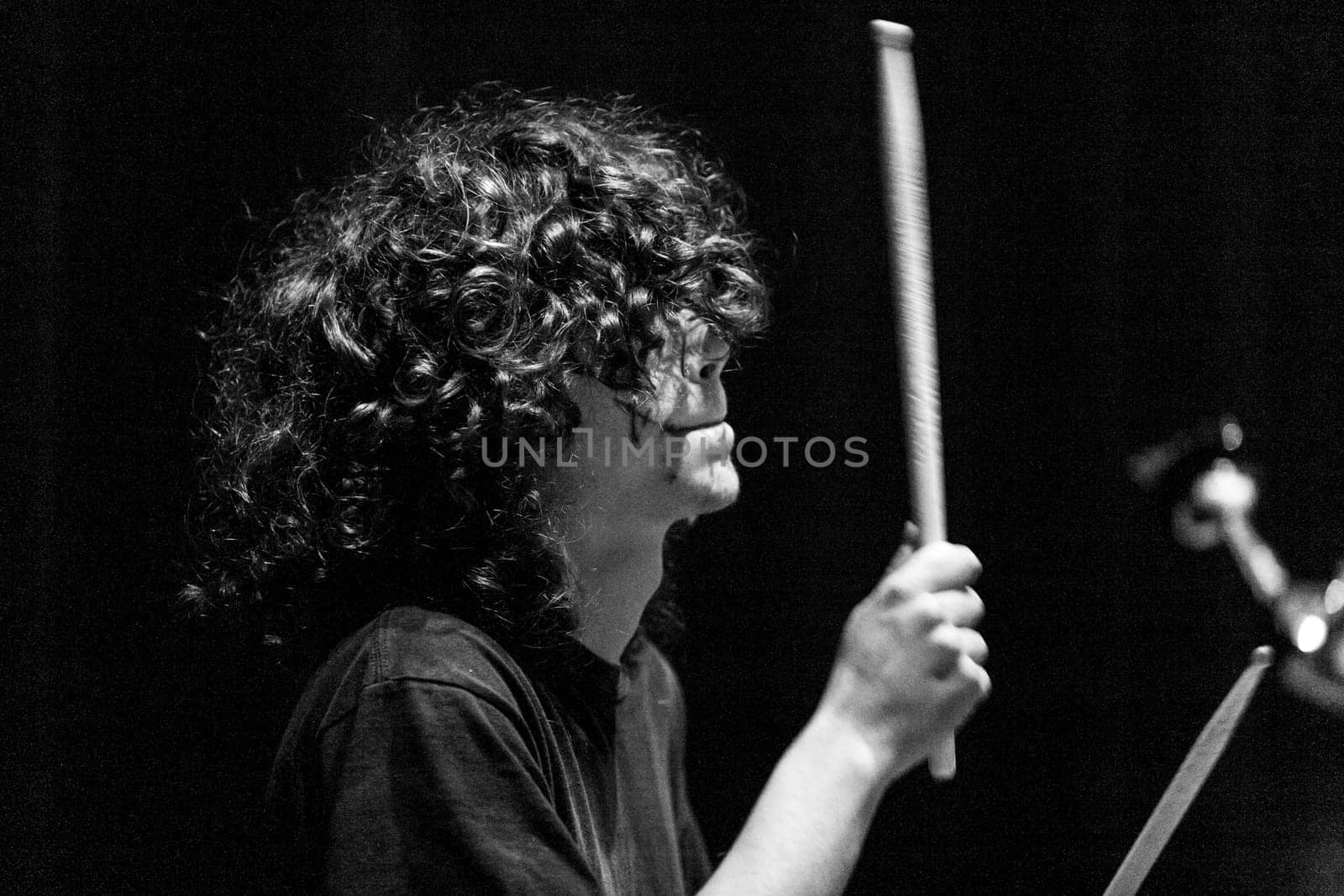 Young drummer, immersed in riveting music, showcases the perfect blend of control and passion. With dark makeup, he embodies the rocker's vigor and speed on stage