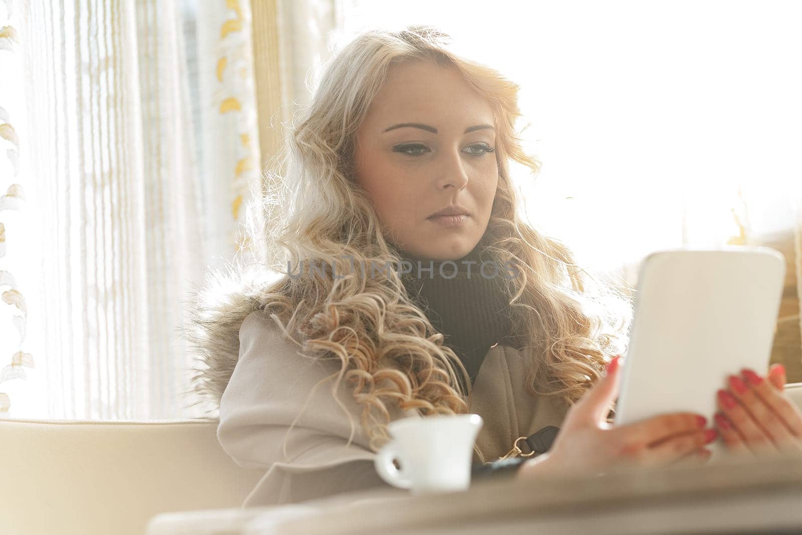 Stunning blonde woman, perfectly dressed, groomed, with makeup and manicure, in a slightly retro elegant European bar, enjoying her espresso while examining her investments and stocks' daily results.