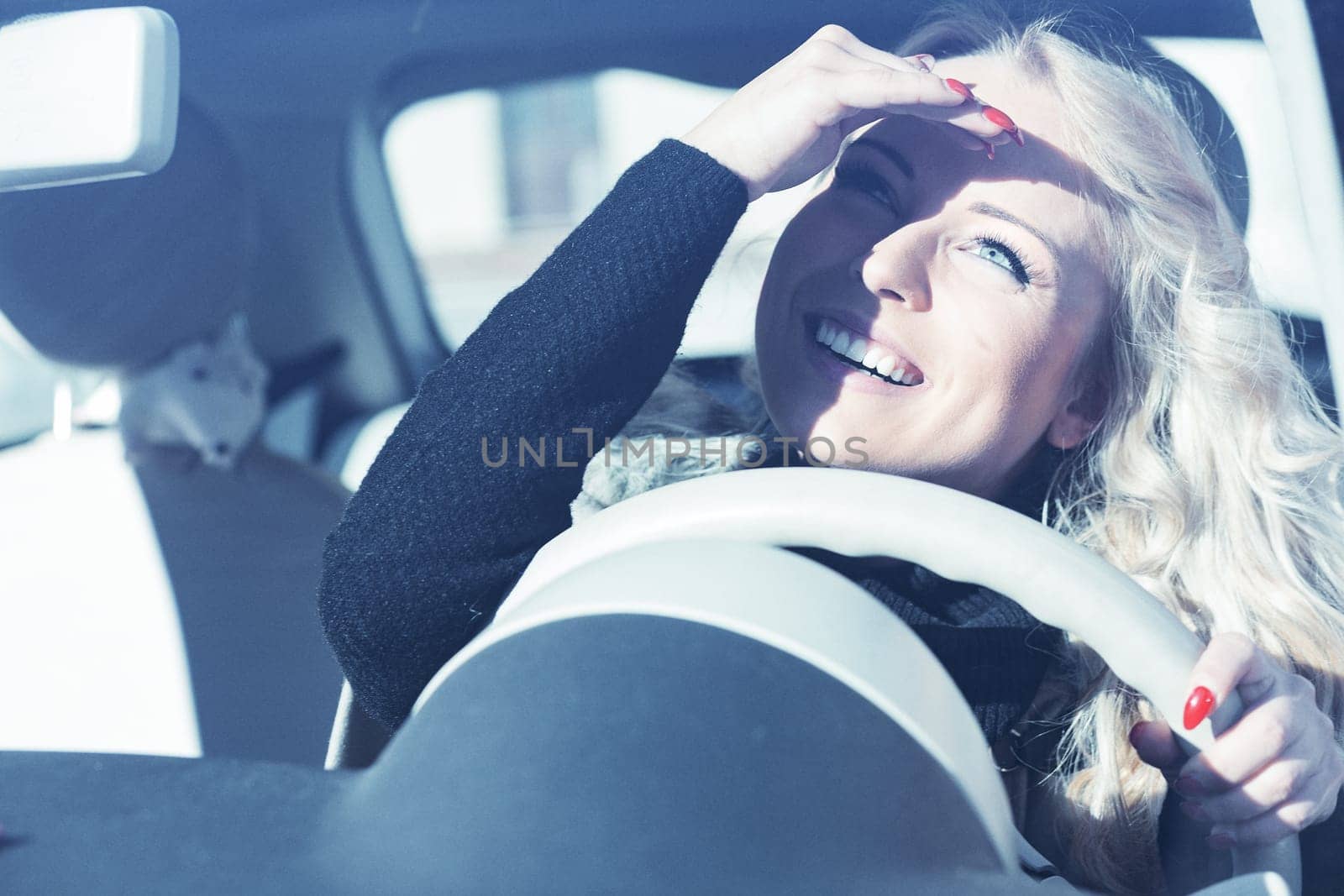 Blonde gal, long curls, flawless makeup, cruising European city in a trendy car. She's all smiles, striking poses, and letting her beautiful eyes shine, while occasionally shading from the sun
