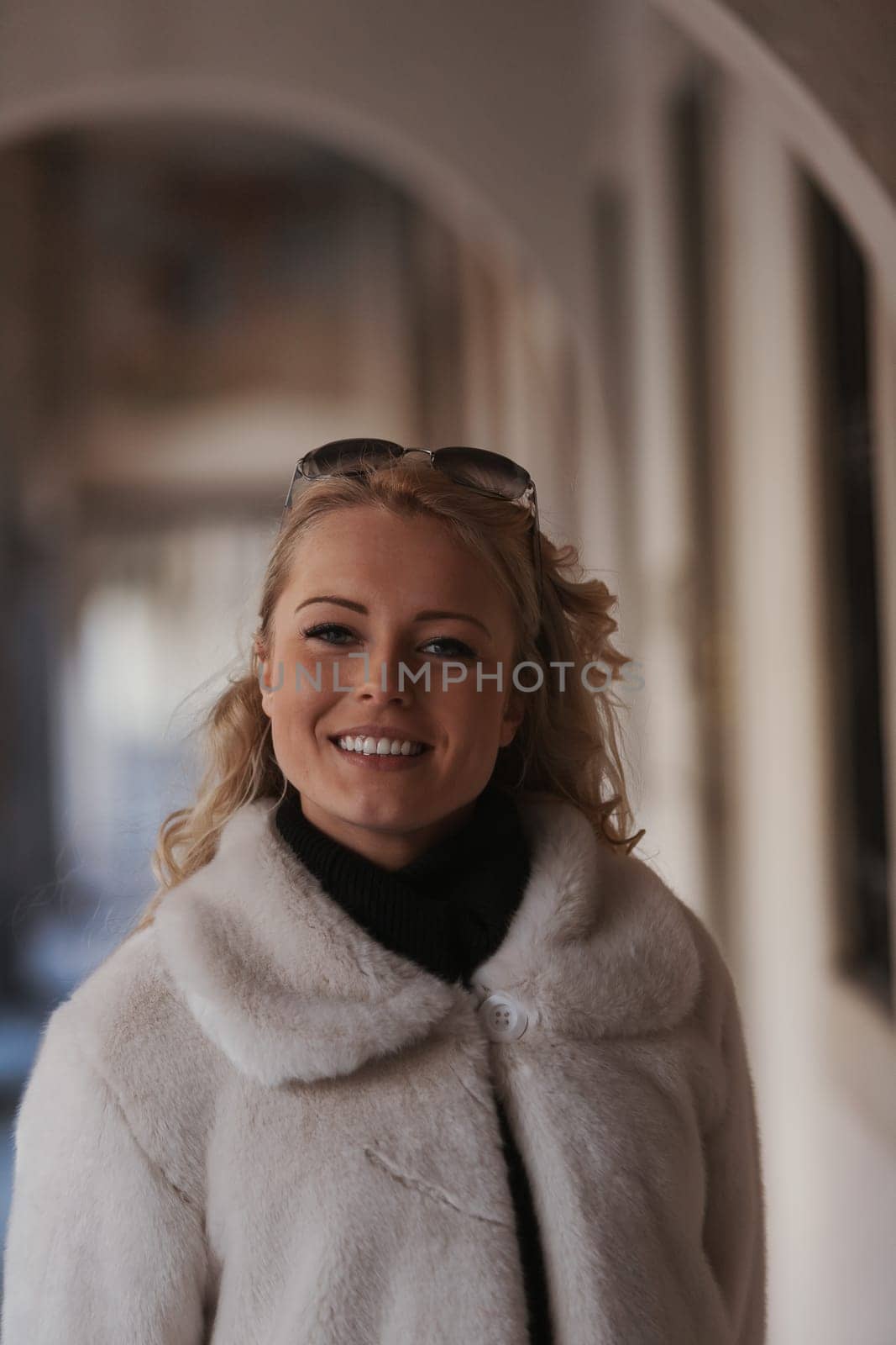 A blonde woman is sightseeing in a historic European city filled with cobblestone streets, archways, marble, and medieval or Gothic elements that have been preserved to appreciate millennial culture a