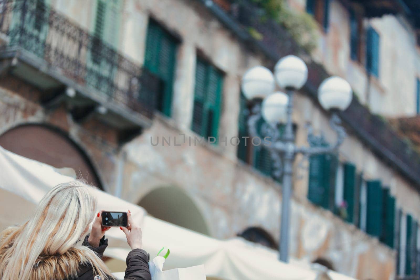 Wide view of an old European city blurred in the background, while a tourist in sharp focus in the lower left is caught taking a photo. A generous amount of copyspace is left for graphic design