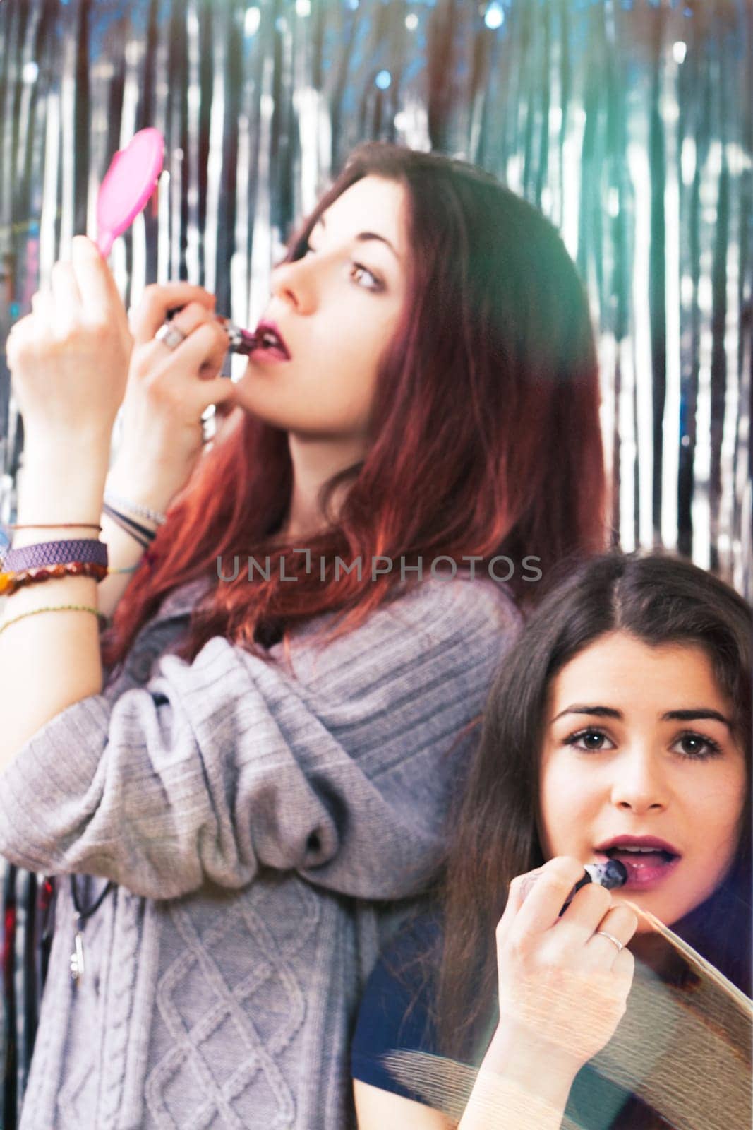 In a club, two vibrant young women touch up their makeup, aiming for allure. Their long dark hair and big eyes highlight their zest for life
