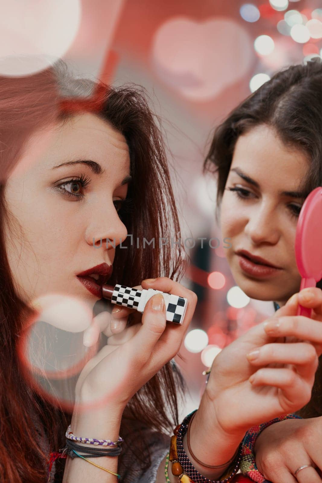 Embodying youthful allure, two women touch up their makeup in a club. Their desire is to feel and be desired as they live the night fully