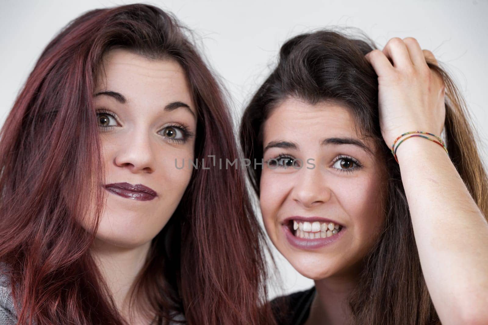 These two women, dressed up with precise makeup and long hair, dont hold back on fun. Making silly faces, they embody the perfect blend of elegance and whimsy
