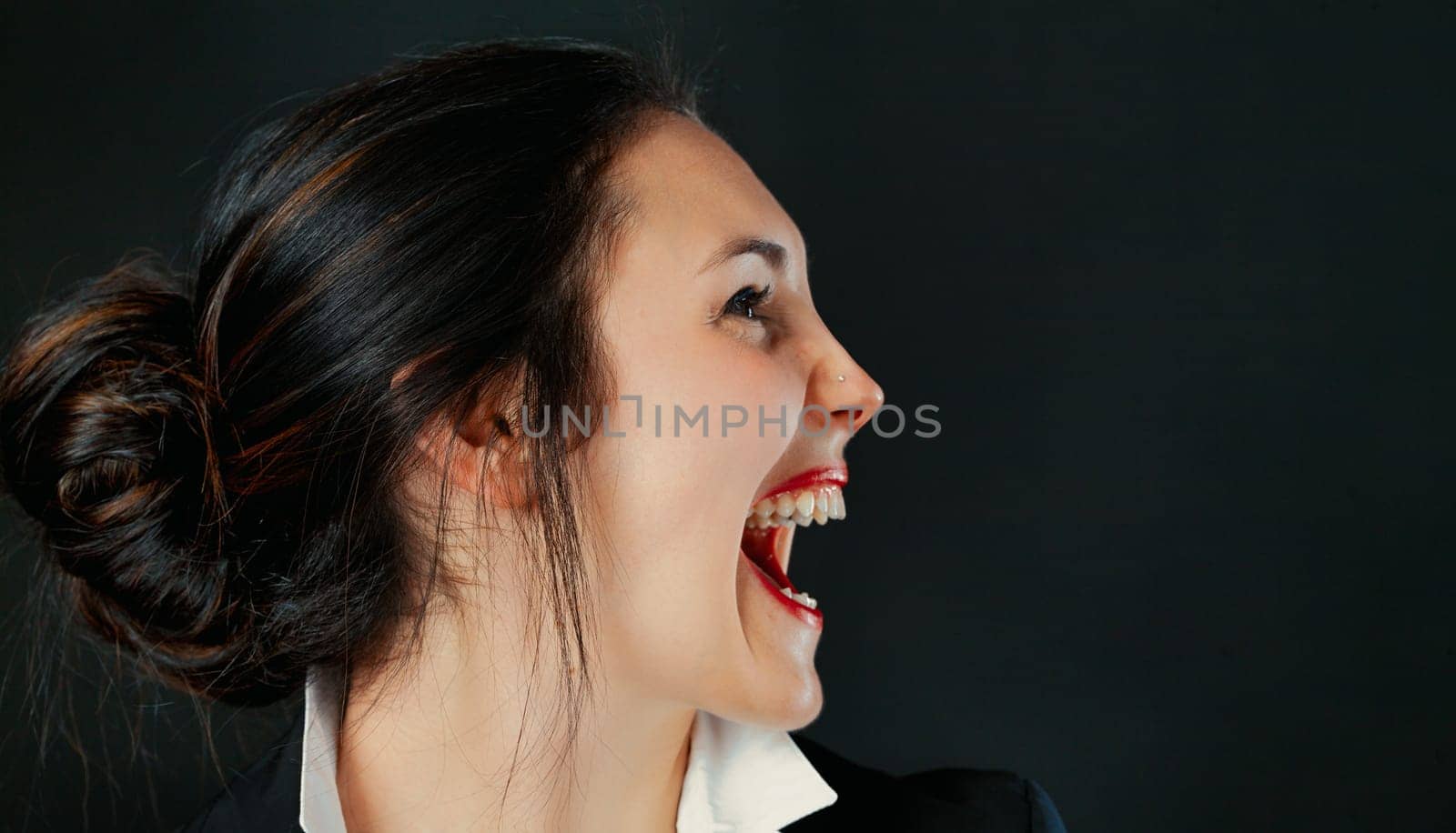 Profile of determined woman. Business champion or temporarily upset? Red lips, tied hair, white blouse, black outerwear. Space right