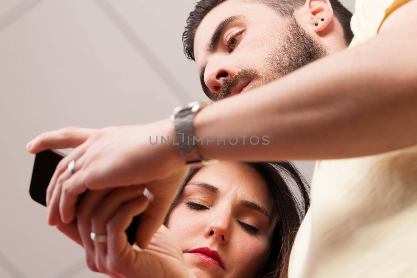 From below, man and woman engrossed in their phones, even when close. Apps, internet, instant messaging, and emails allow constant work, highlighting the double-edged sword of technology