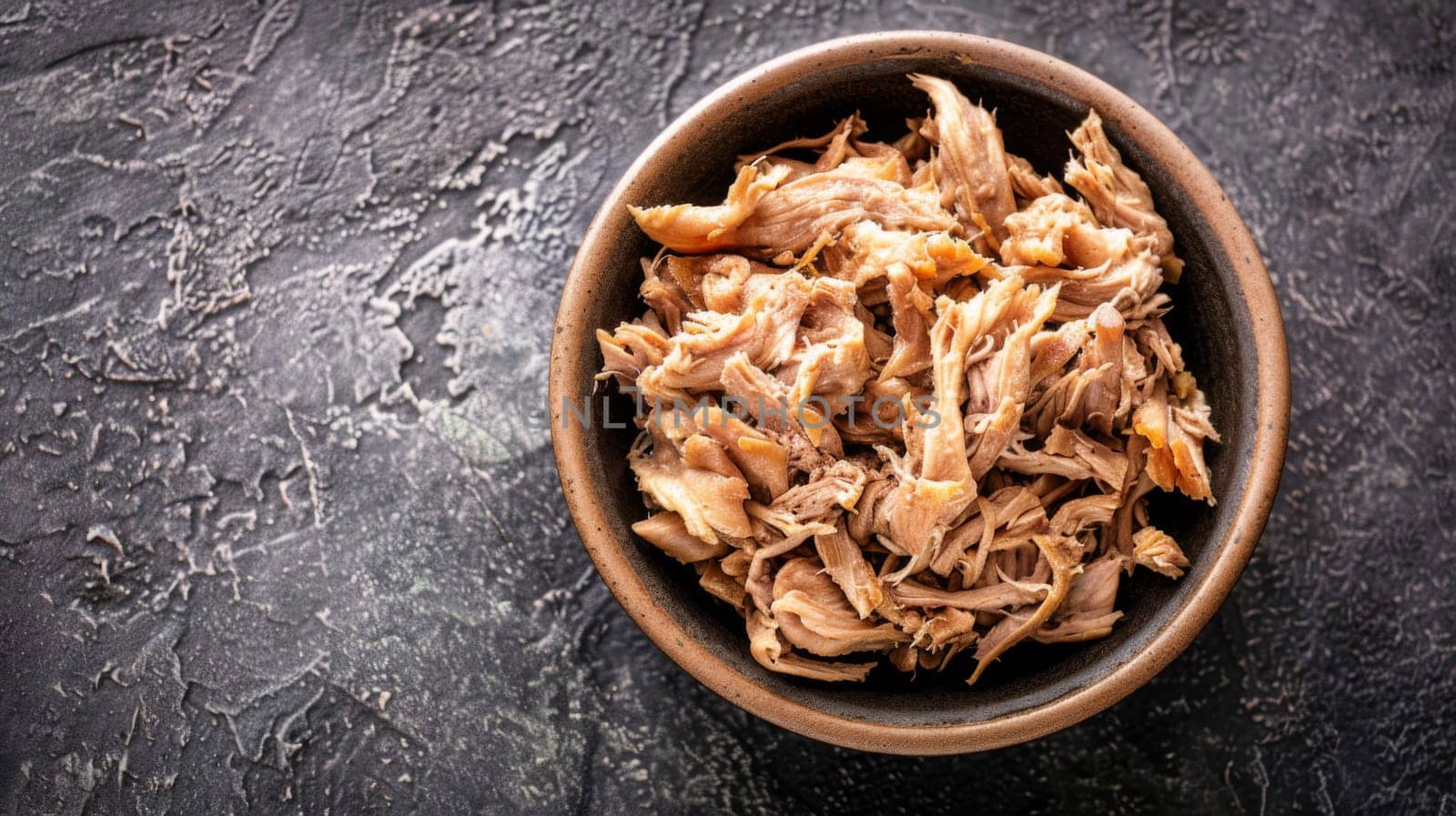 A brown bowl sits on top of a wooden table, filled to the brim with savory meat. The dish exudes rich aromas and looks ready to be enjoyed for a meal.