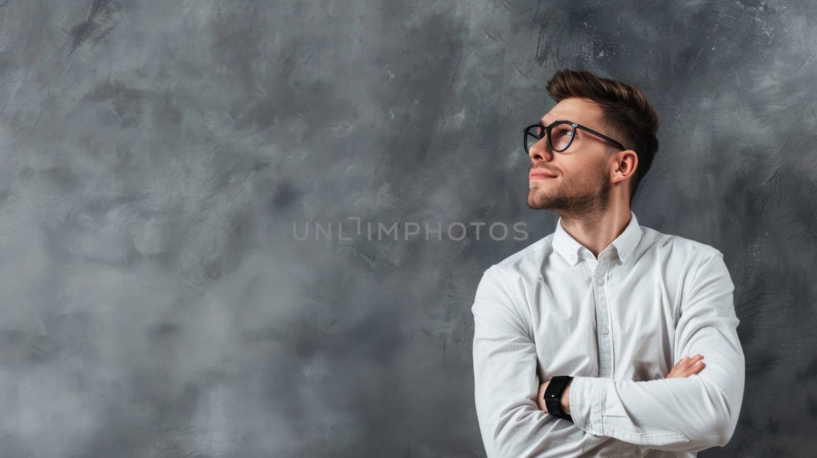 A man wearing glasses stands with his arms crossed in a confident pose. He appears focused and thoughtful, showcasing determination and authority.