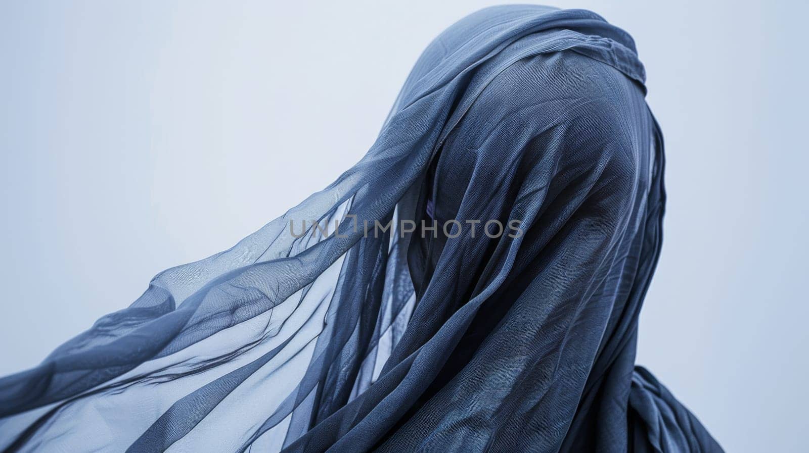 A woman stands with a veil covering her head. The veil is intricately designed and draped elegantly over her hair. She looks poised and regal.