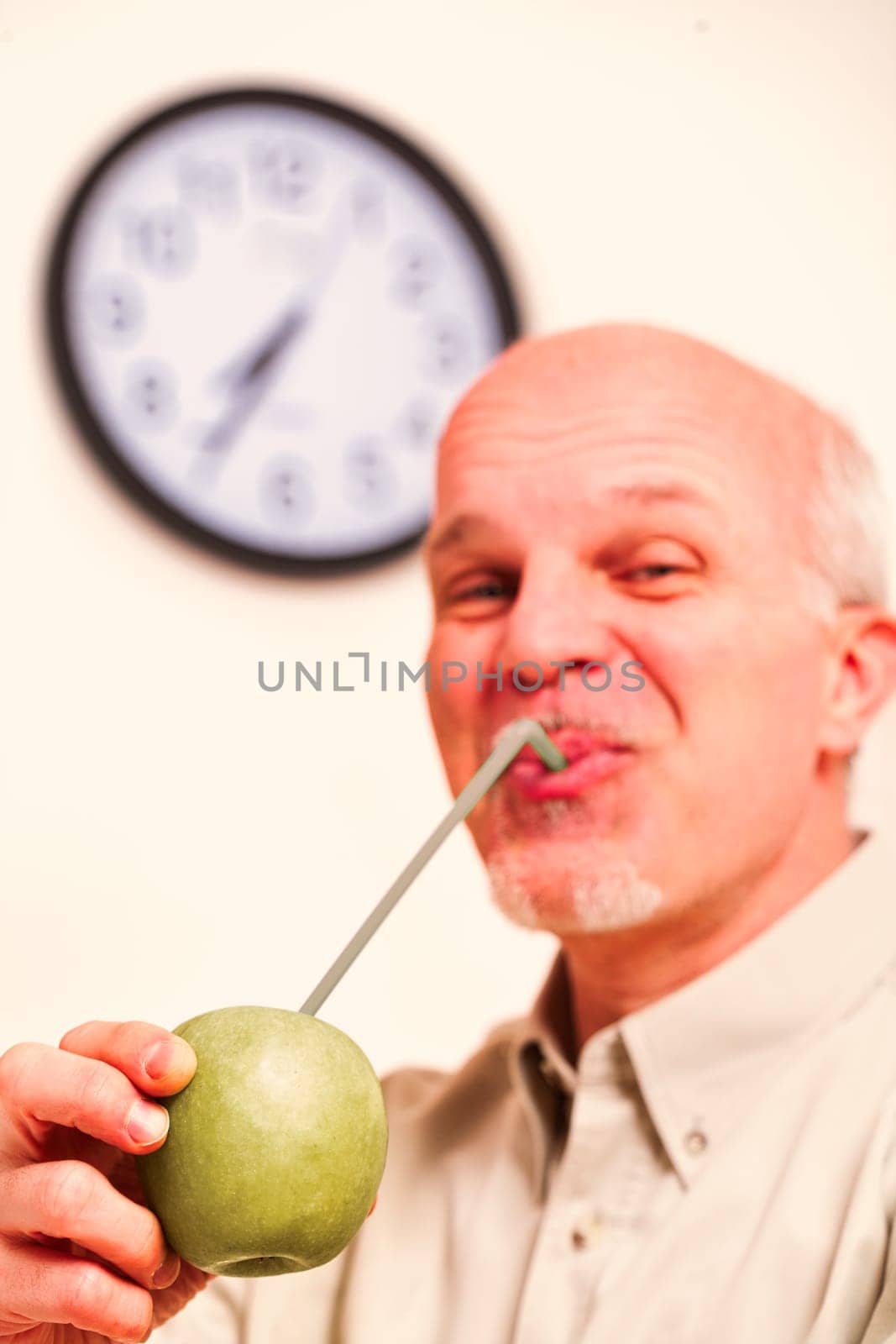 Apple in focus. An elderly man believes the proverb: an apple a day keeps the doctor away. In his kitchen, he's a playful joker but values fruit quality while savoring each vitamin drop