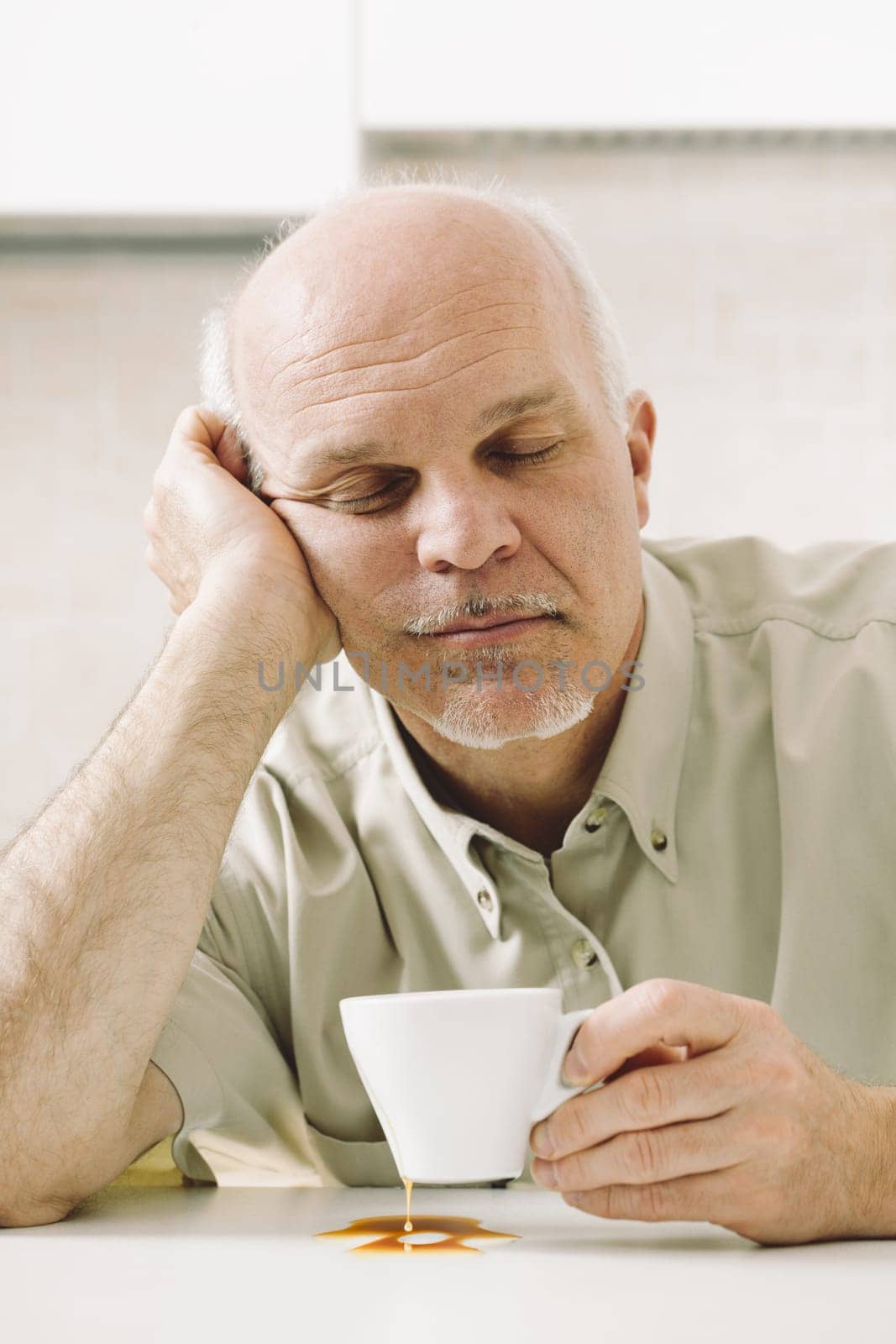 Elderly man, weary from awakening, struggles with his morning coffee. Sleep deprivation impacts his job. Retirement age rises but not his salary. Medical aid for sleep and reduced stress is crucial