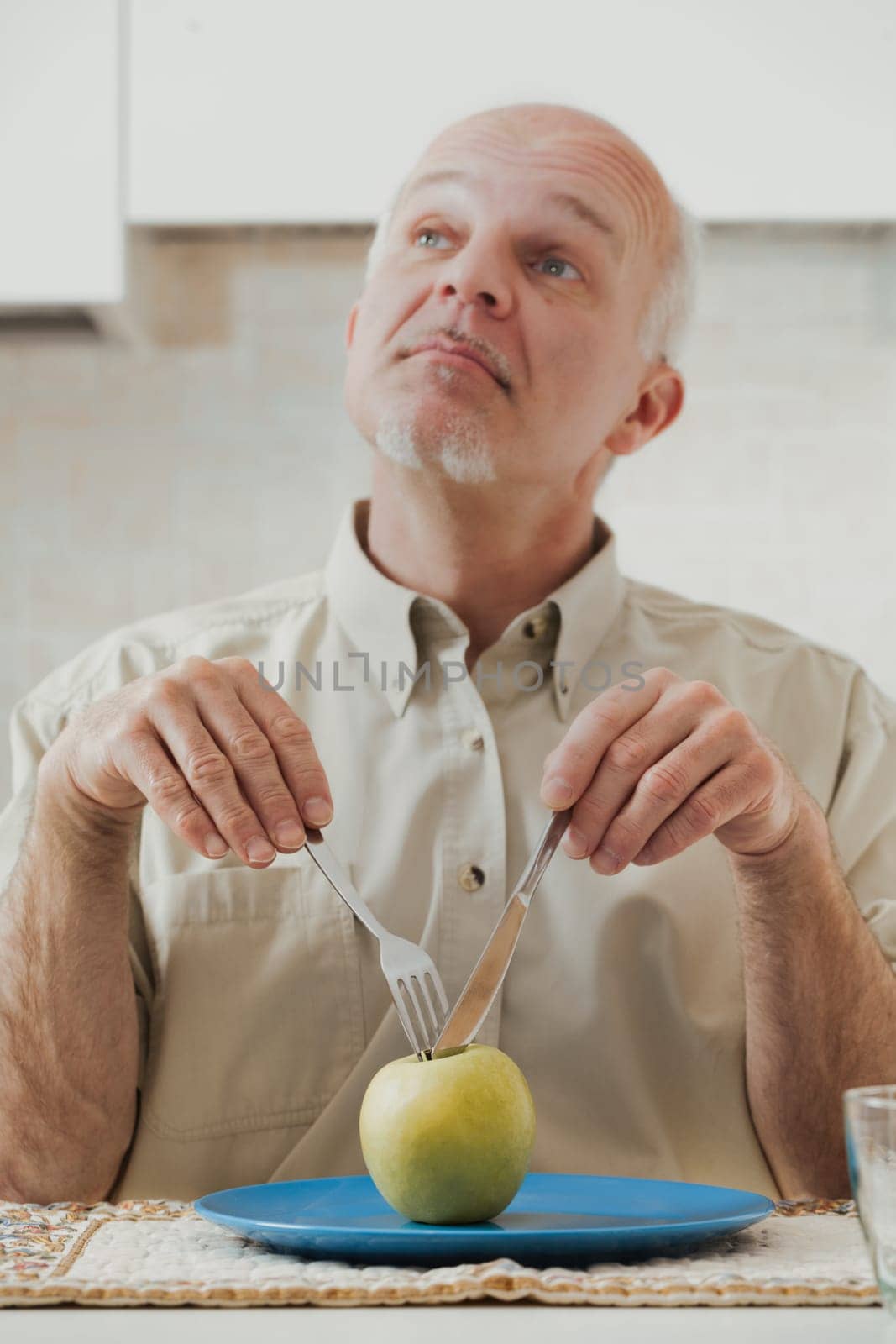 green apple sits before an old man who's poised to eat. Using utensils and making comical expressions, he secretly loathes his diet, longing for tasty, high-fat, and sugary foods. Yet, the medical war