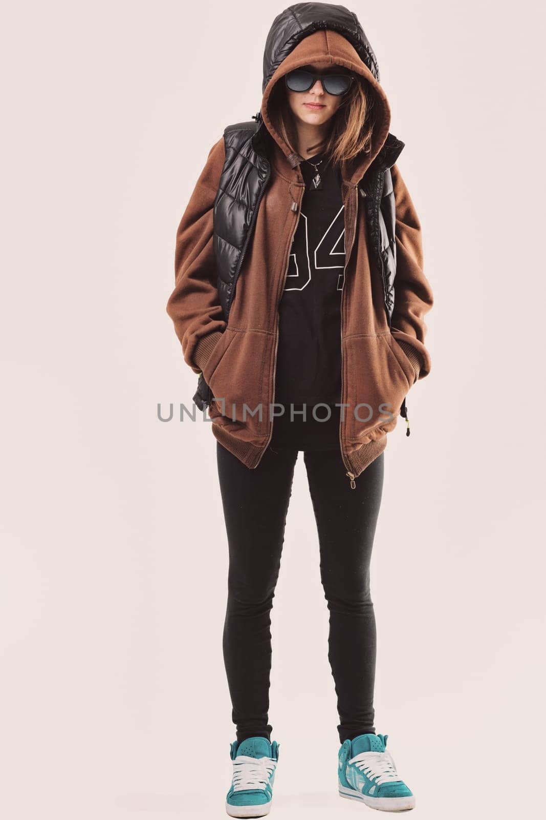The woman sports a streetwear style with sunglasses, a hoodie, and sneakers.