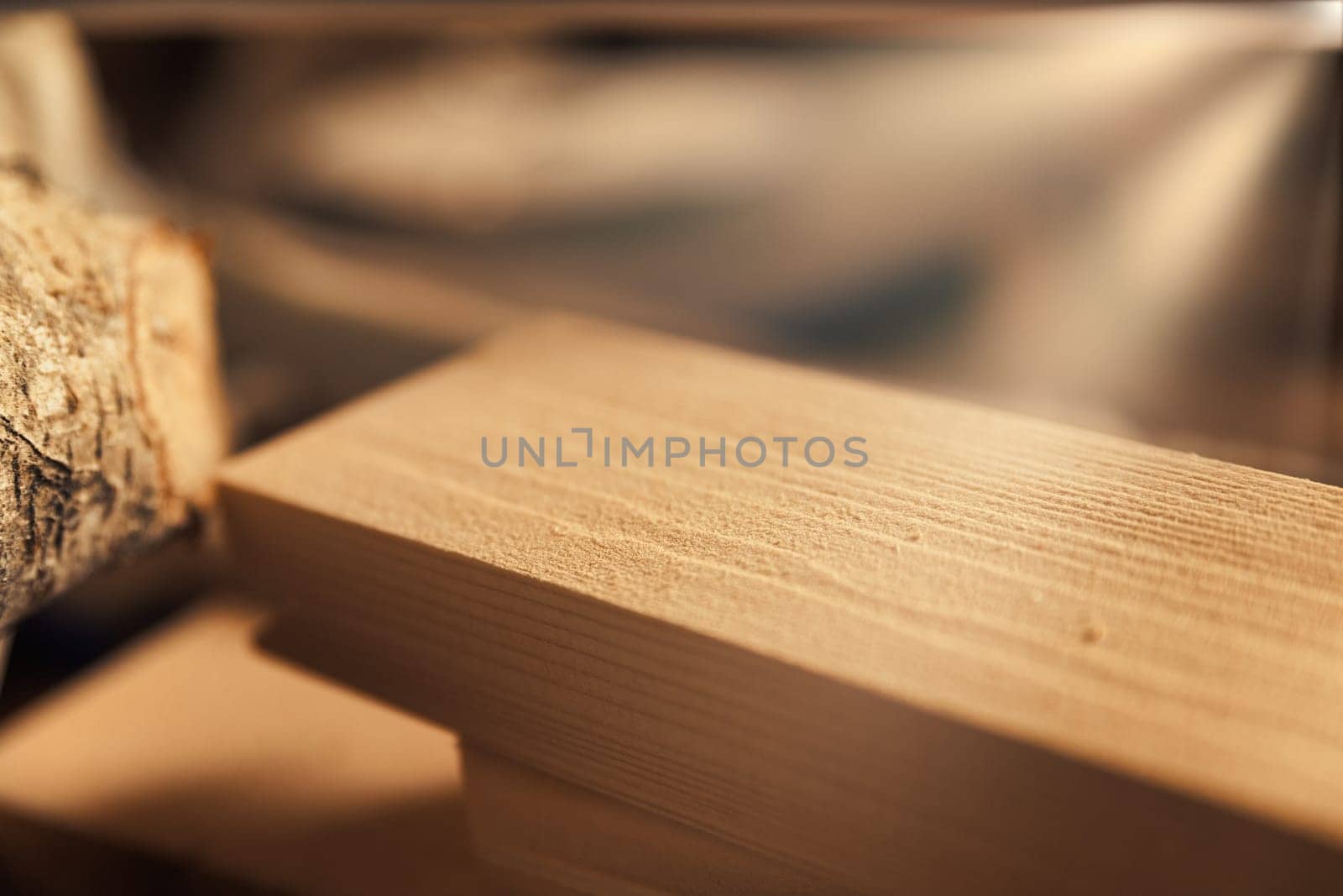 Rays of light streaming in through the large window of a carpentry shop hit rough-hewn boards and pieces of wood, ready for further processing, materials to be touched.