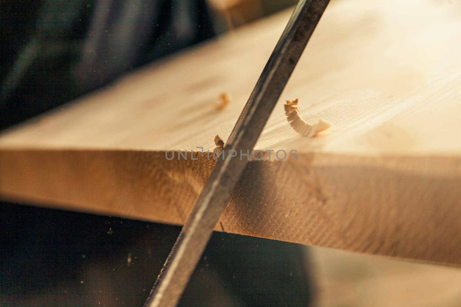 Detail of a hand-cutting blade notching the first corners of a board, obtaining wood curls and bevels in the surface, often intentionally irregular. Wood craftsmanship.