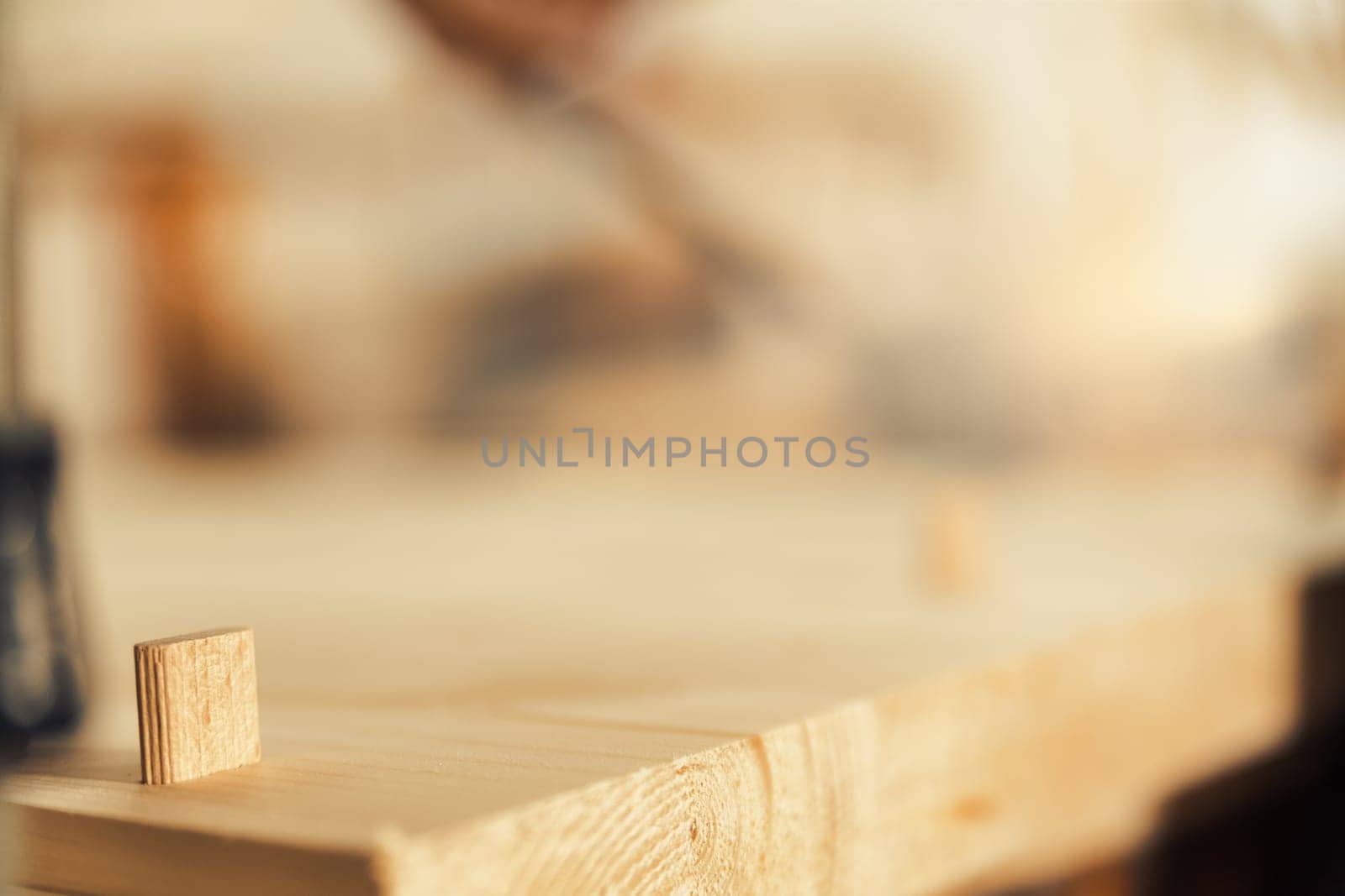 Focused detail in wood. A small dowel seems to be looking at the expanse of the board, blurred. Excellent background full of copyspace on woodworking topic.