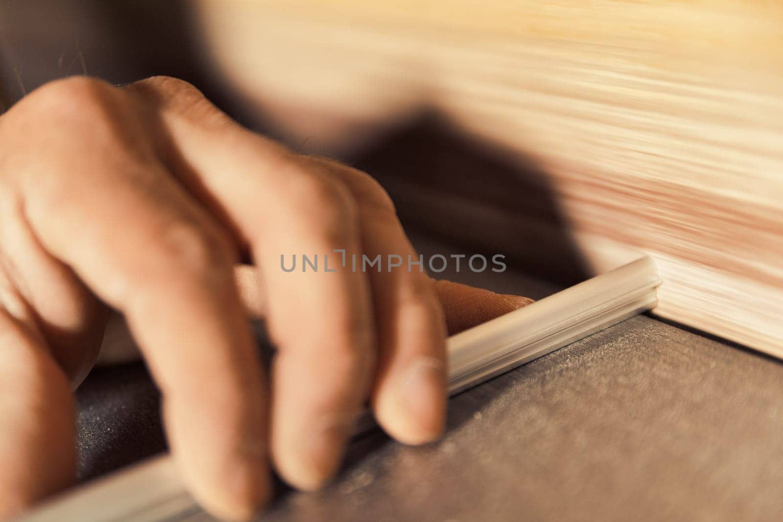 In sharp focus, the woodworker's hands carefully position, insert, and fix components of handmade furniture in his workshop. He thinks before he acts with skill and determination. The background is bl