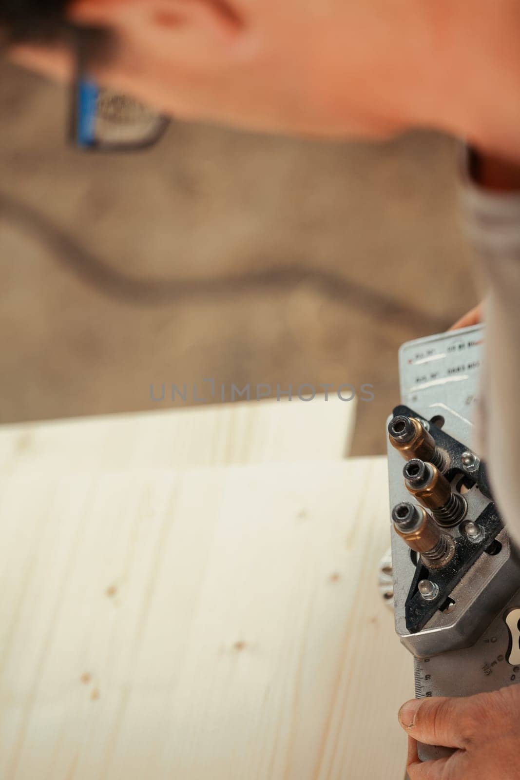 Detail in focus of a drilling jig used by the woodworker in his craft workshop. Although they can be self-made the multi-pattern carpenter's drilling jigs are convenient and professional.