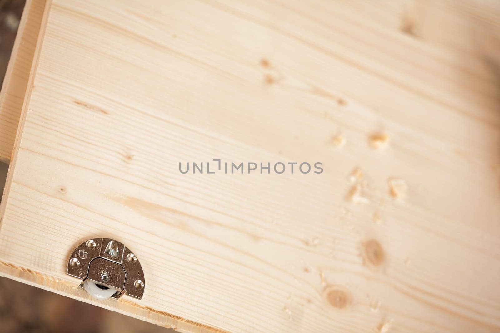 Metal detail inserted into a wooden component that will form a piece of furniture handcrafted in a carpenter's workshop. Wheel that will slide a drawer or shelf.
