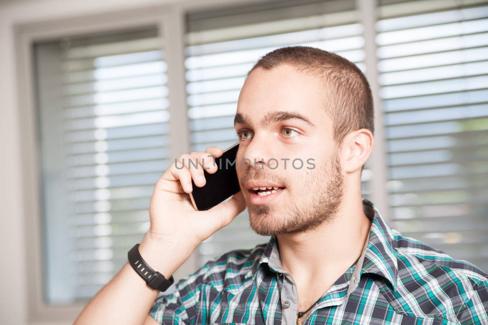Casually dressed young male engaged in a phone conversation indoors