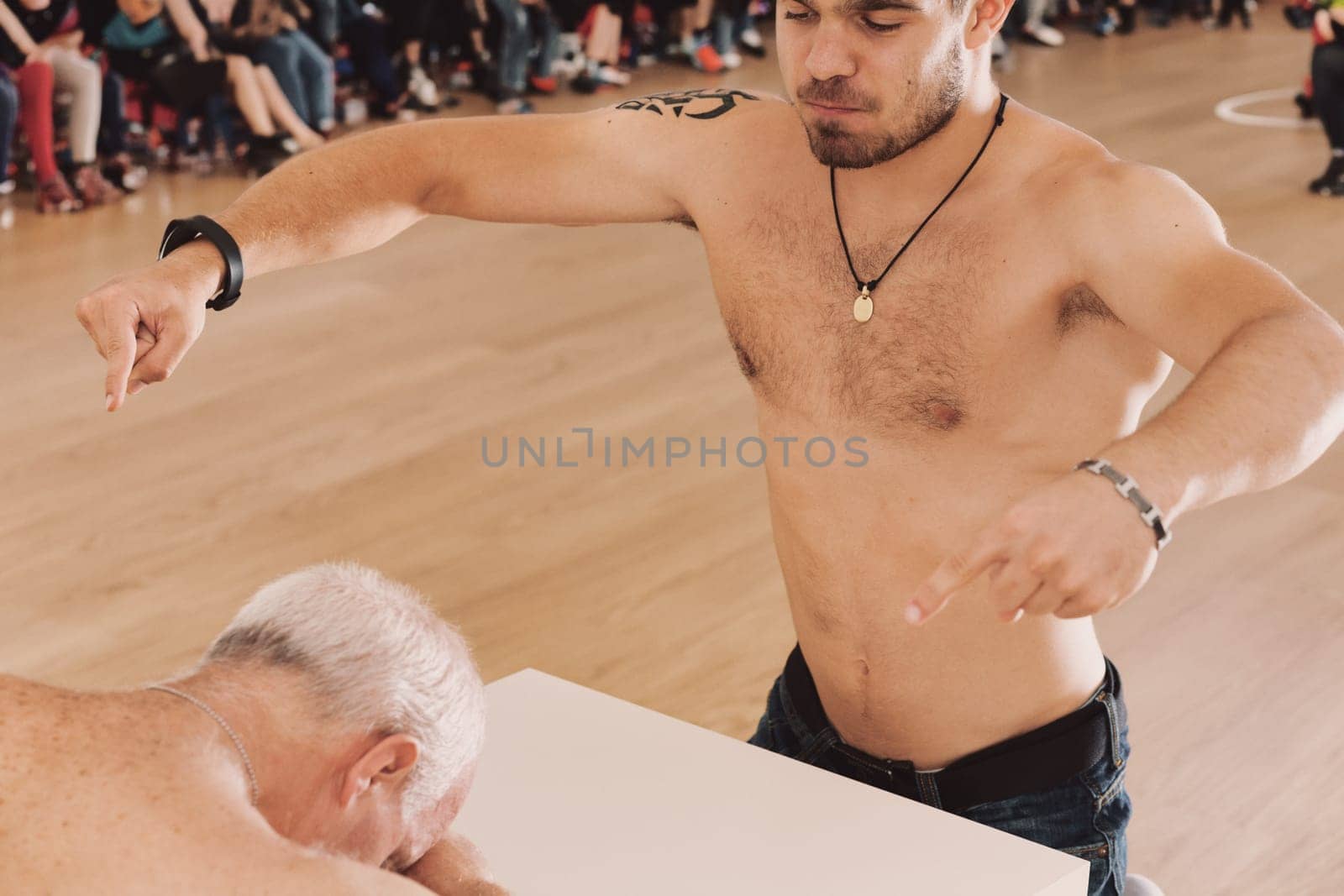 young athlete triumphs in arm wrestling, mockingly demanding submission from the elder
