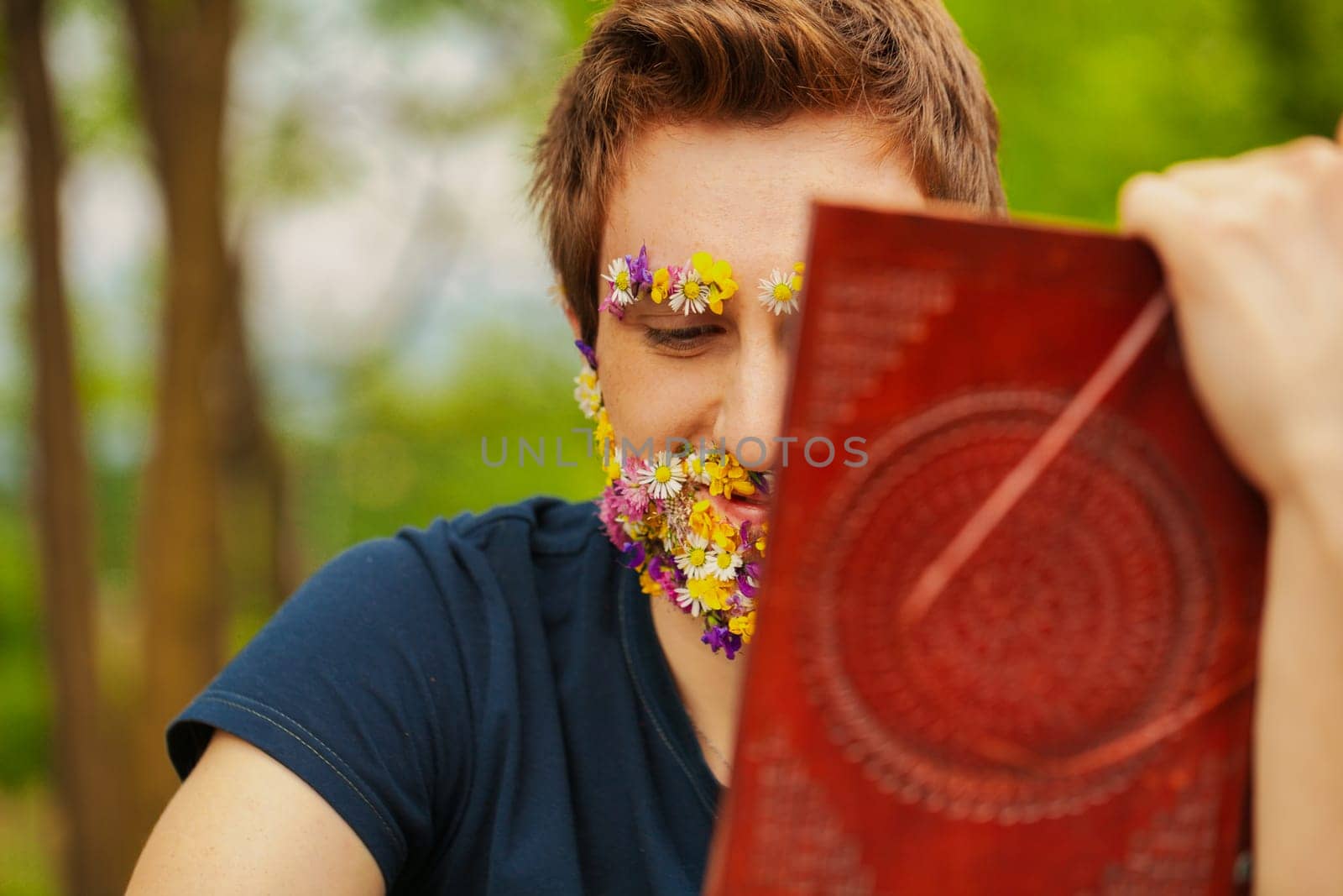 The woods envelop a man whose face, rather unusually, is adorned with floral beauty. He finds solace reading a classic leather book