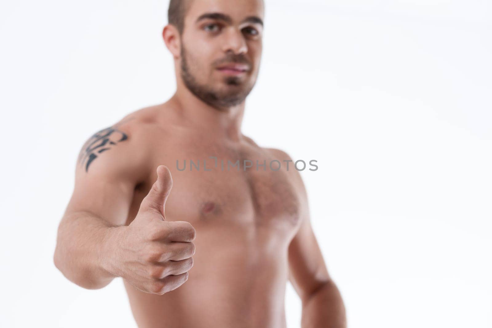 Confident gaze from a tattooed man displaying approval with a thumbs-up gesture