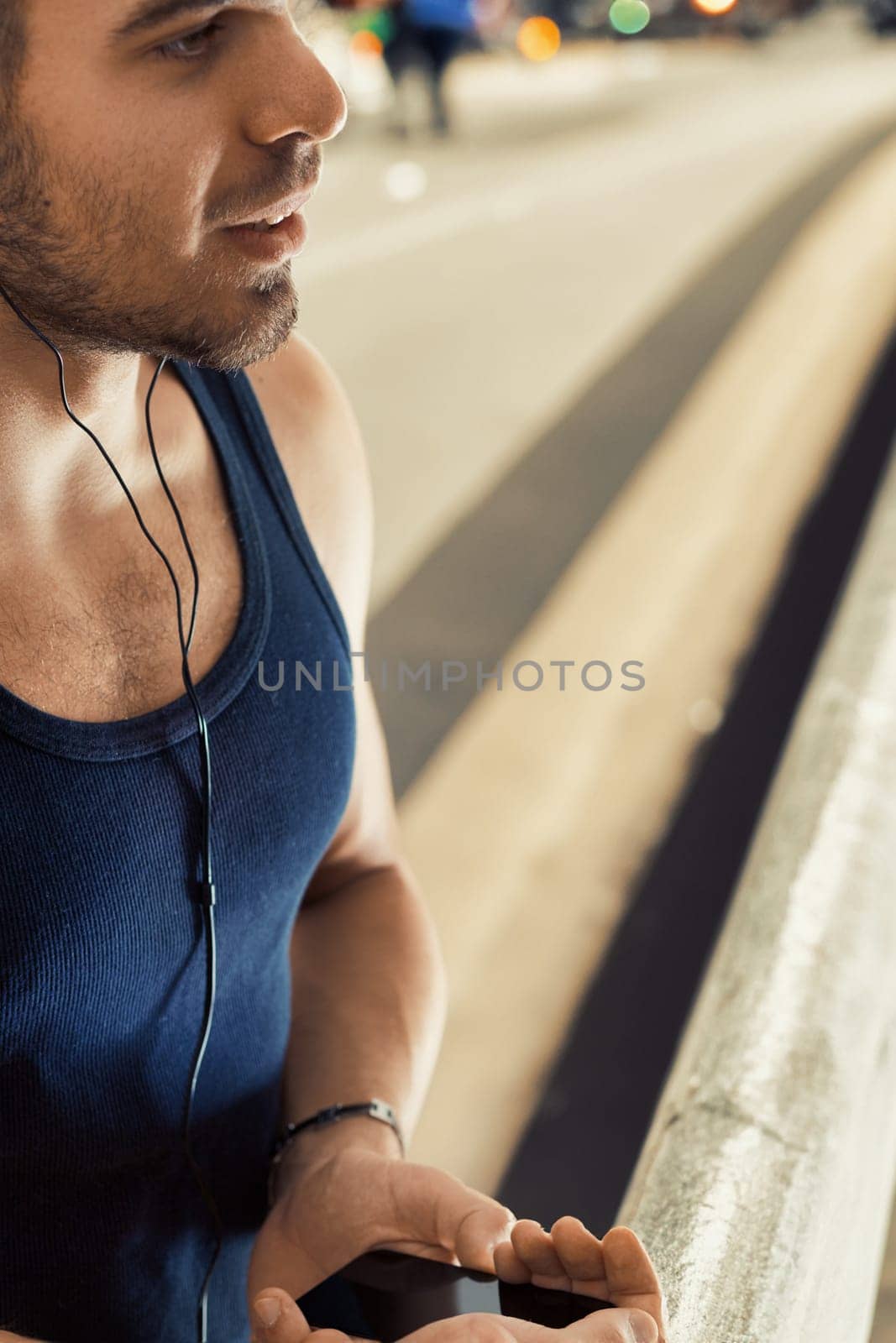 Athlete in blue tank top unwinds with music post-exercise