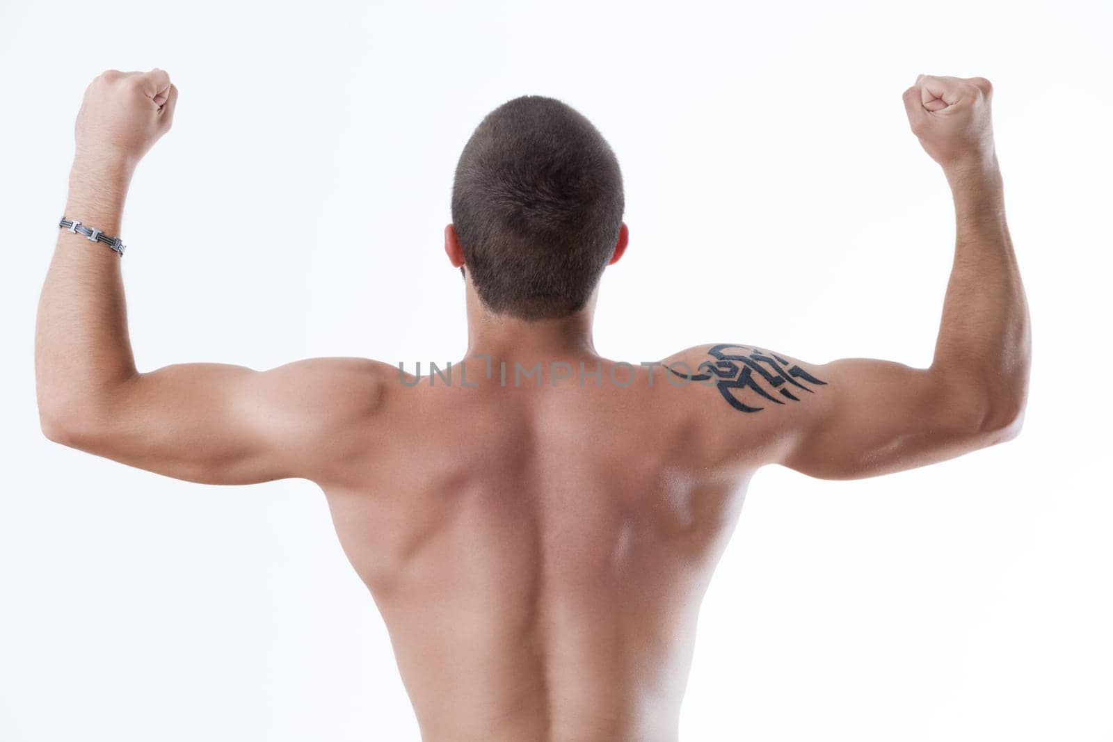 Athletic physique from behind, arms up in triumph, tattoo accentuated