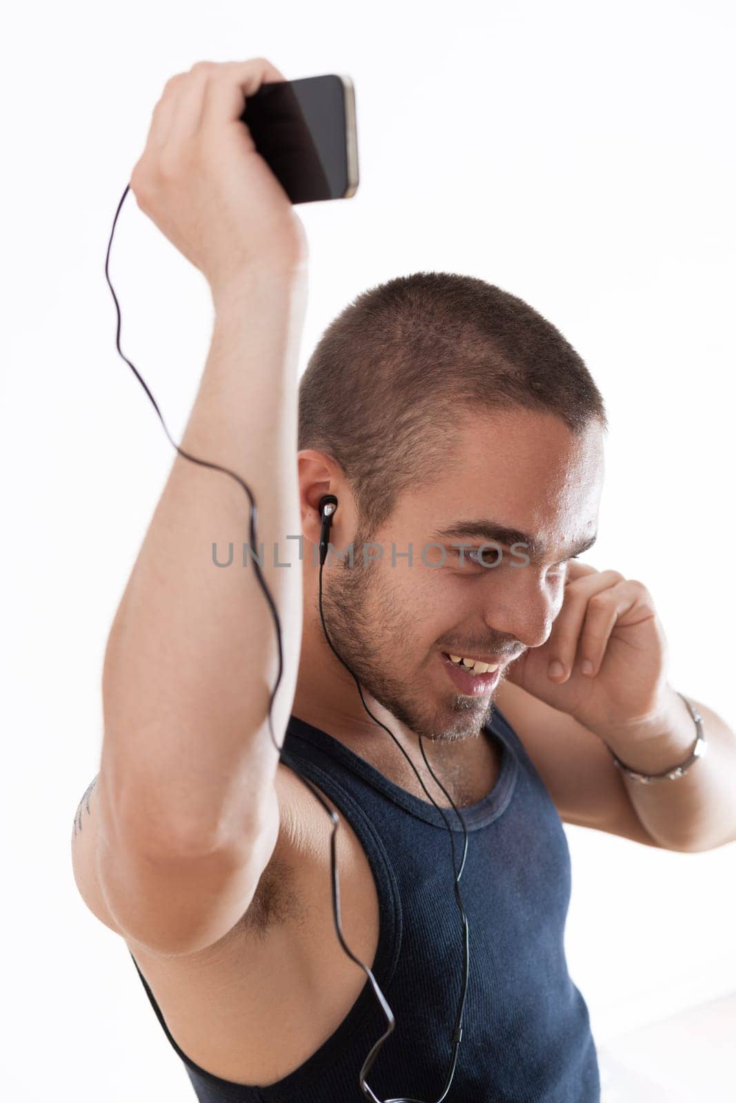 Enthusiastic young man enjoys music, holding his phone aloft with earphones in