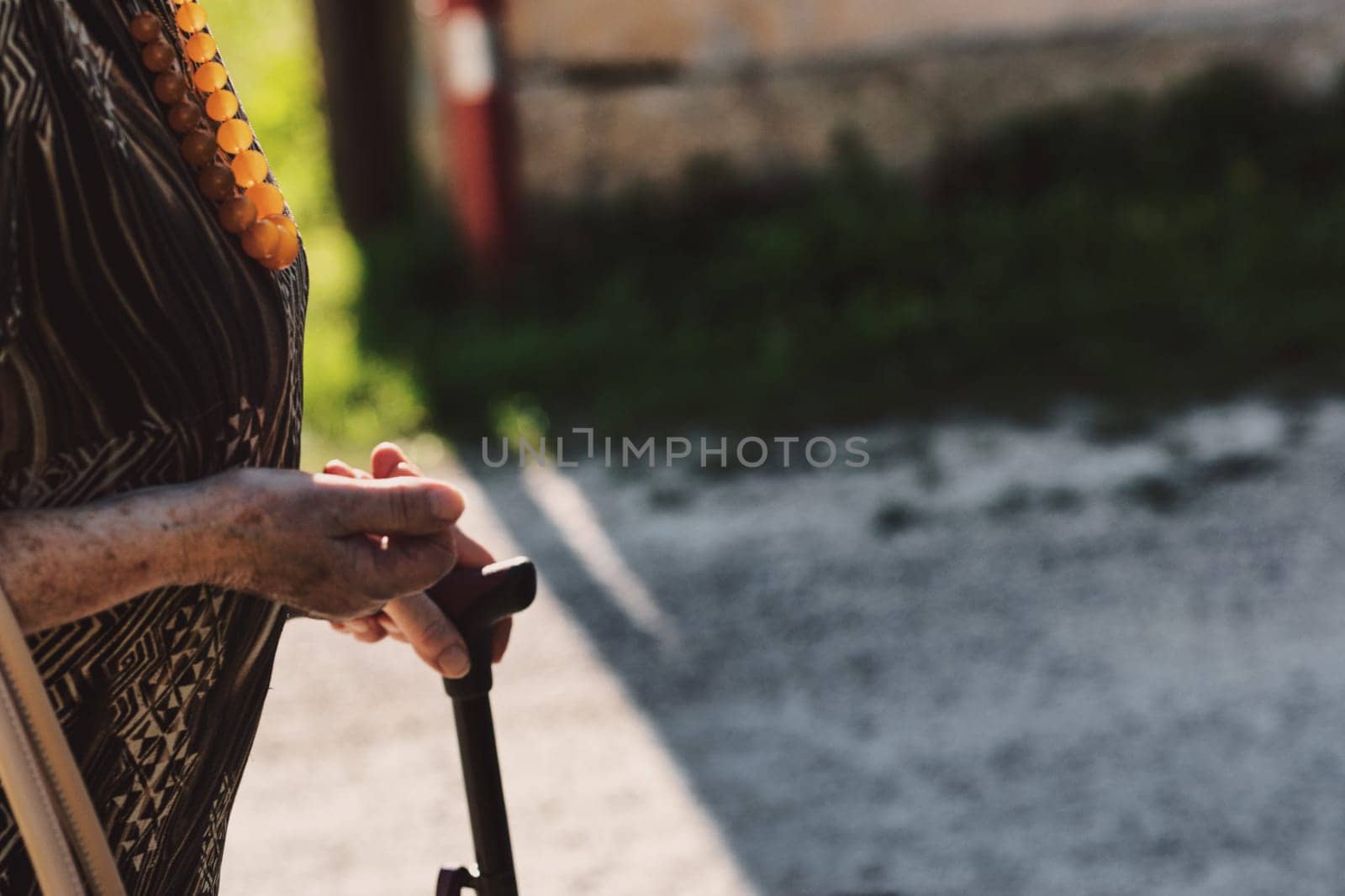 Her blemished hand on the stick epitomizes survival with purpose. Walking in the open air serves as her remedy for better circulation and overall well-being