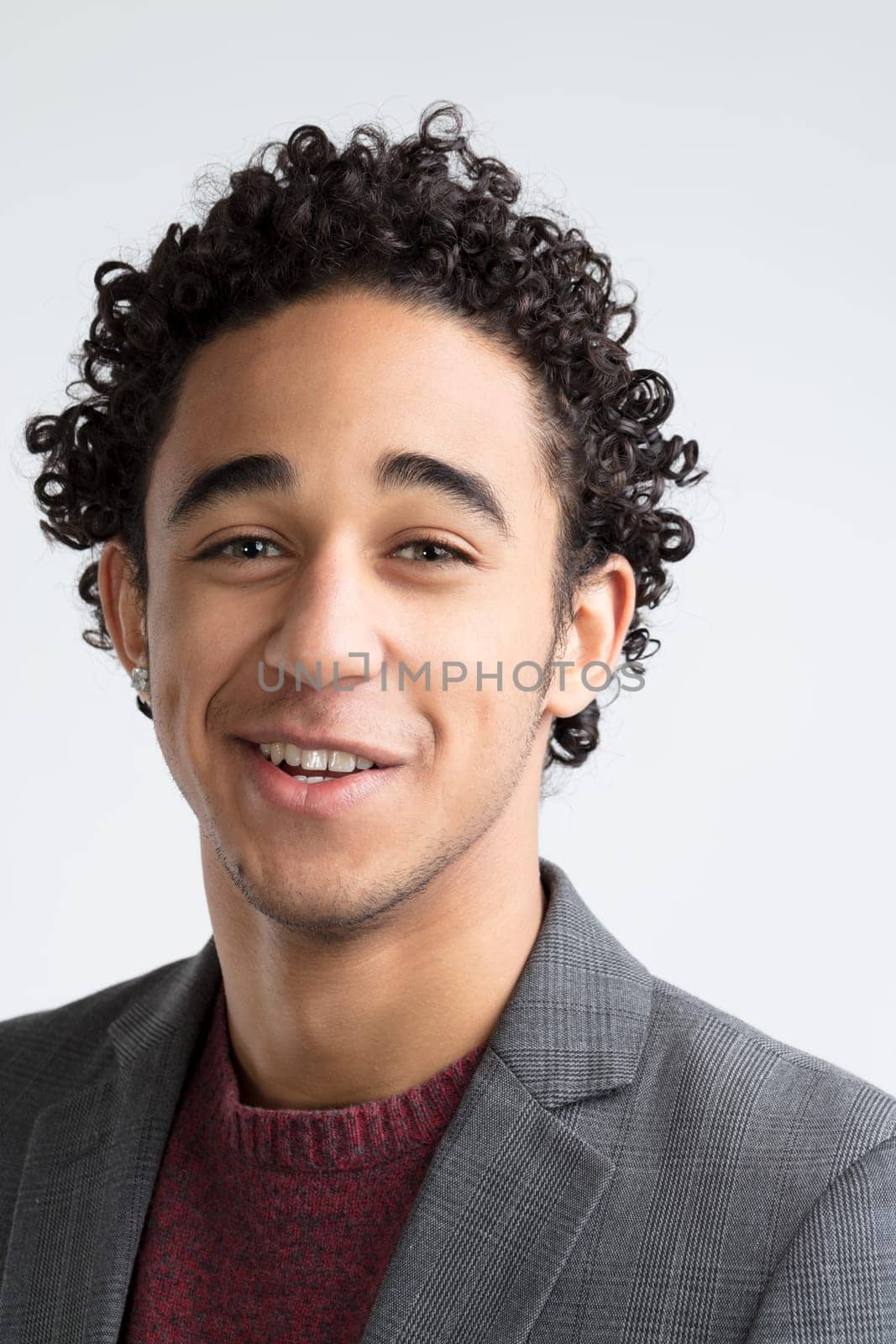With expressive eyes and curly locks, the man's attire suggests a balance of casual and formal