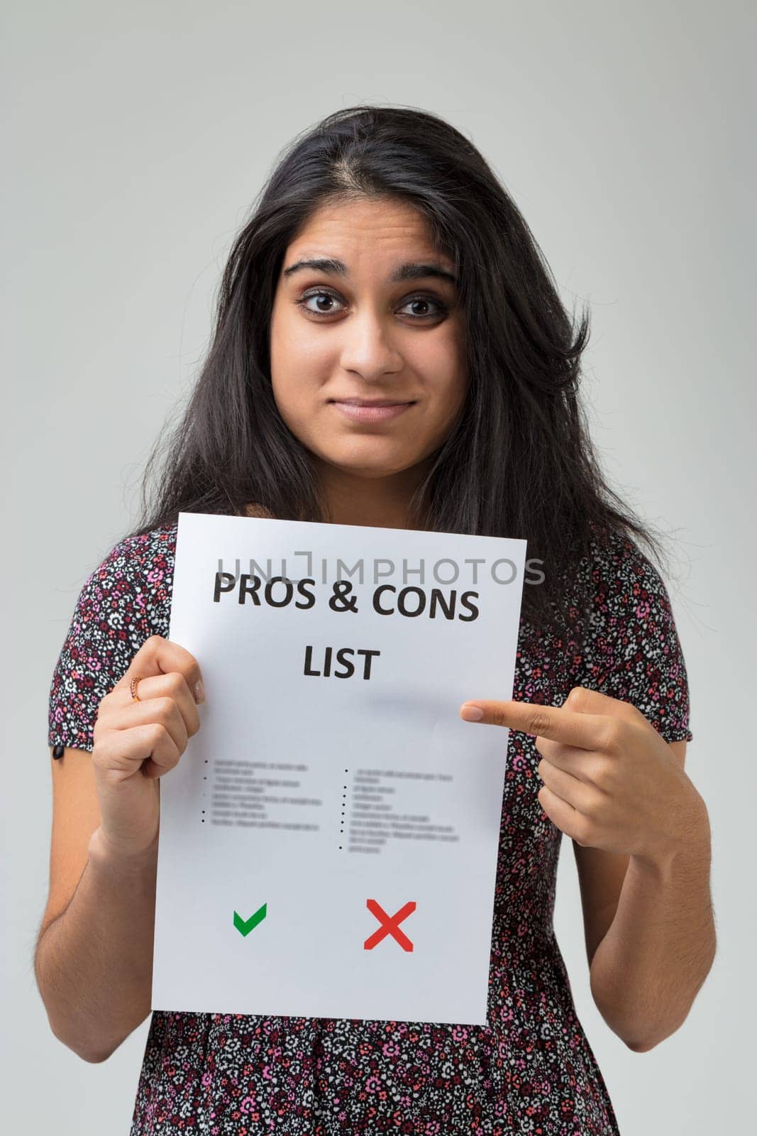Navigating a decision, a woman in a patterned dress showcases a 'Pros & Cons List.' Her expression reveals contemplation, while the green tick and red cross hint at her dilemma
