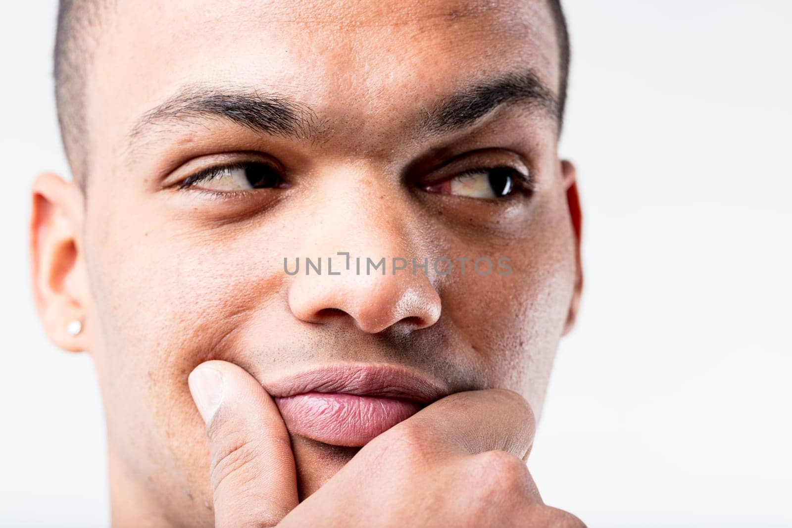 A black man's close-up portrait. He's either pondering a lucrative idea or doubting someone's integrity, as he pensively rubs his lower face