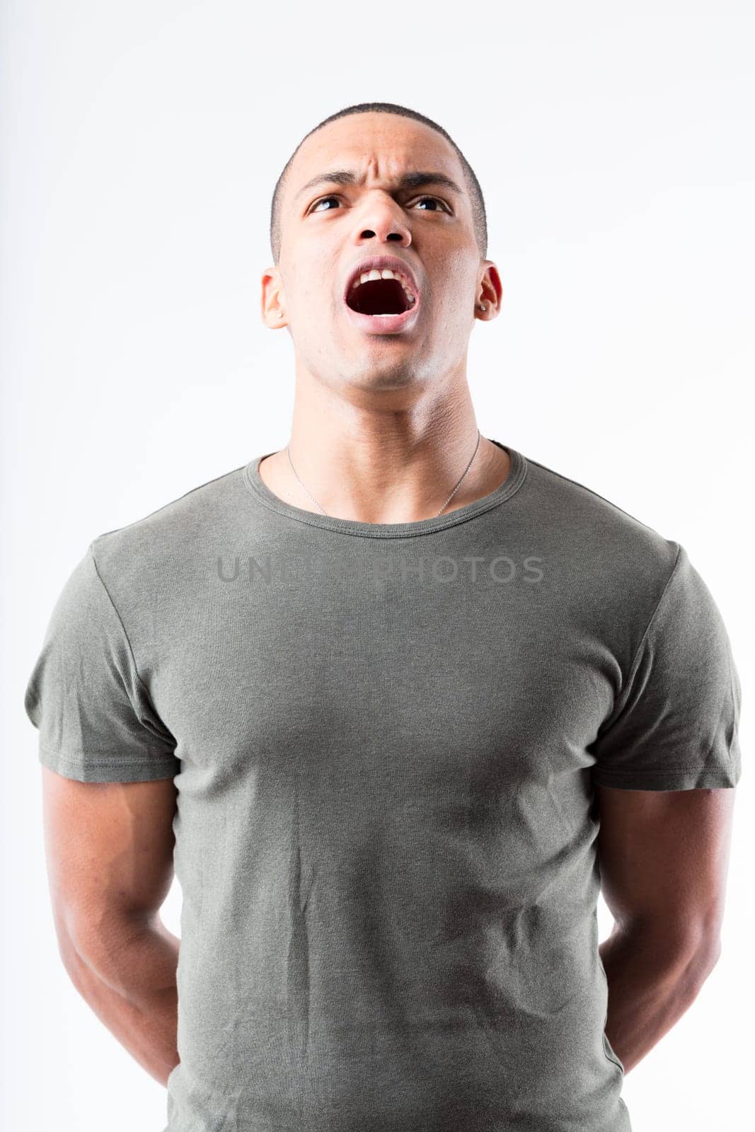 A man in military-style pose, shouting assertively. His high chin, puffed chest, broad shoulders, shaved head, and his military green shirt are isolated from the background