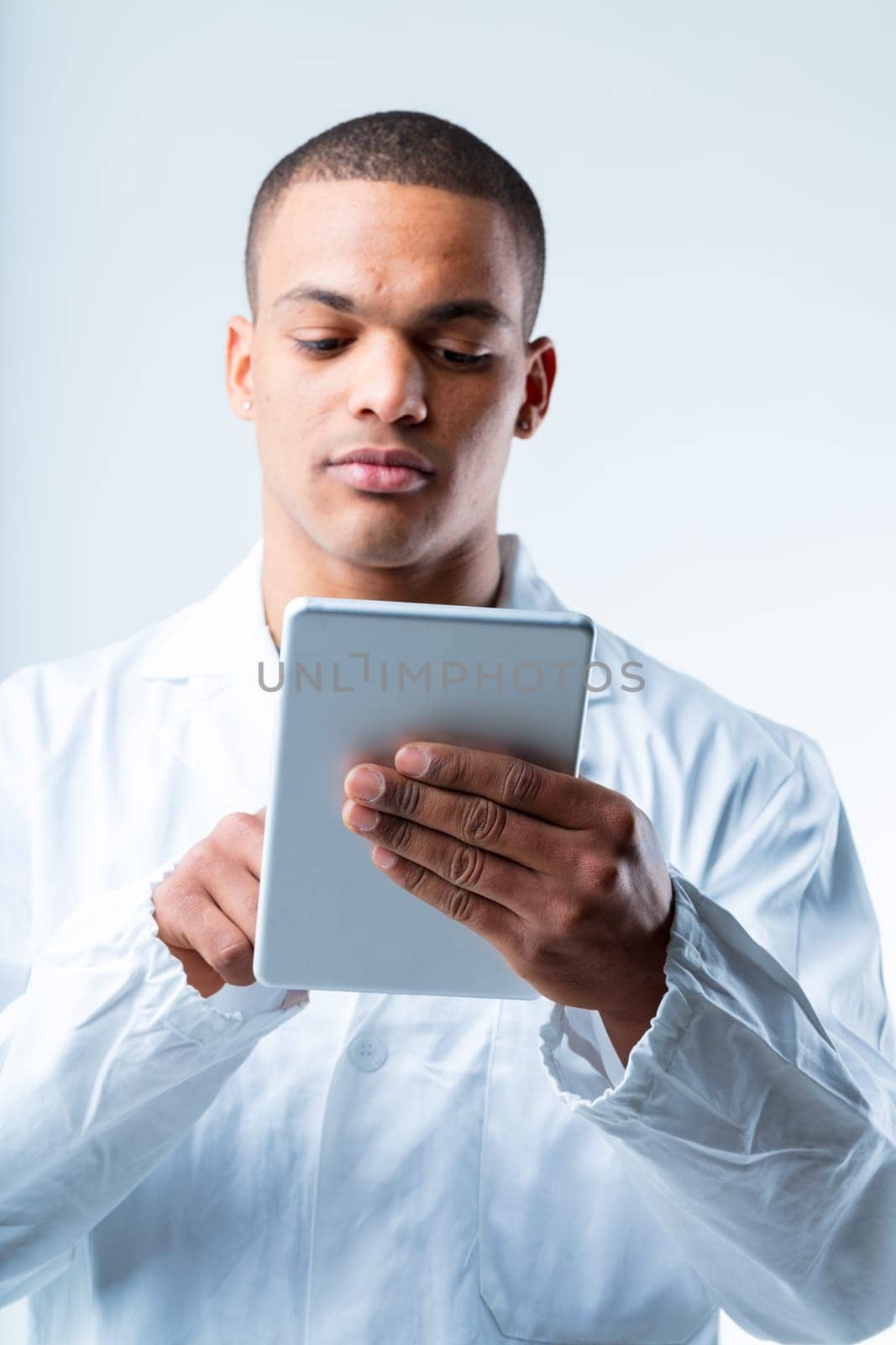 Lab technician with tablet. Black man in white coat is an expert researcher, scientist, or lab tech. He uses his device to monitor analysis results, data, and connects online