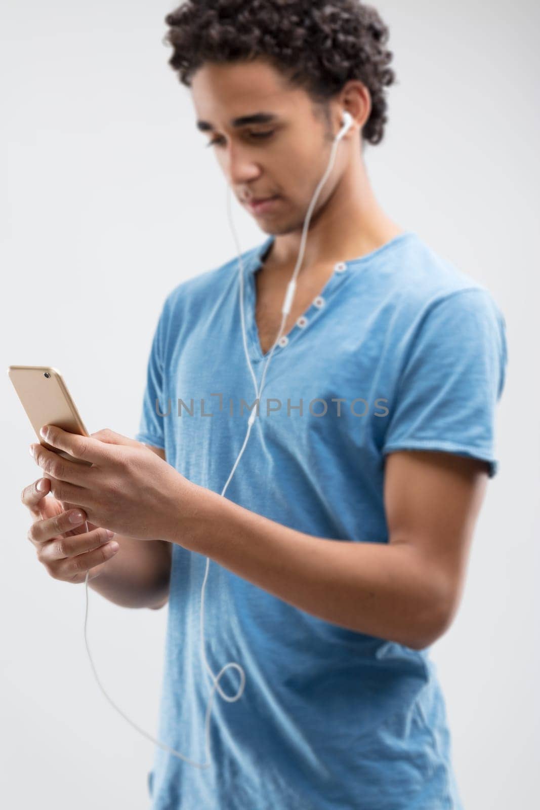 Young man in blue appears captivated by his phone's content, perhaps engrossed in a melody or article