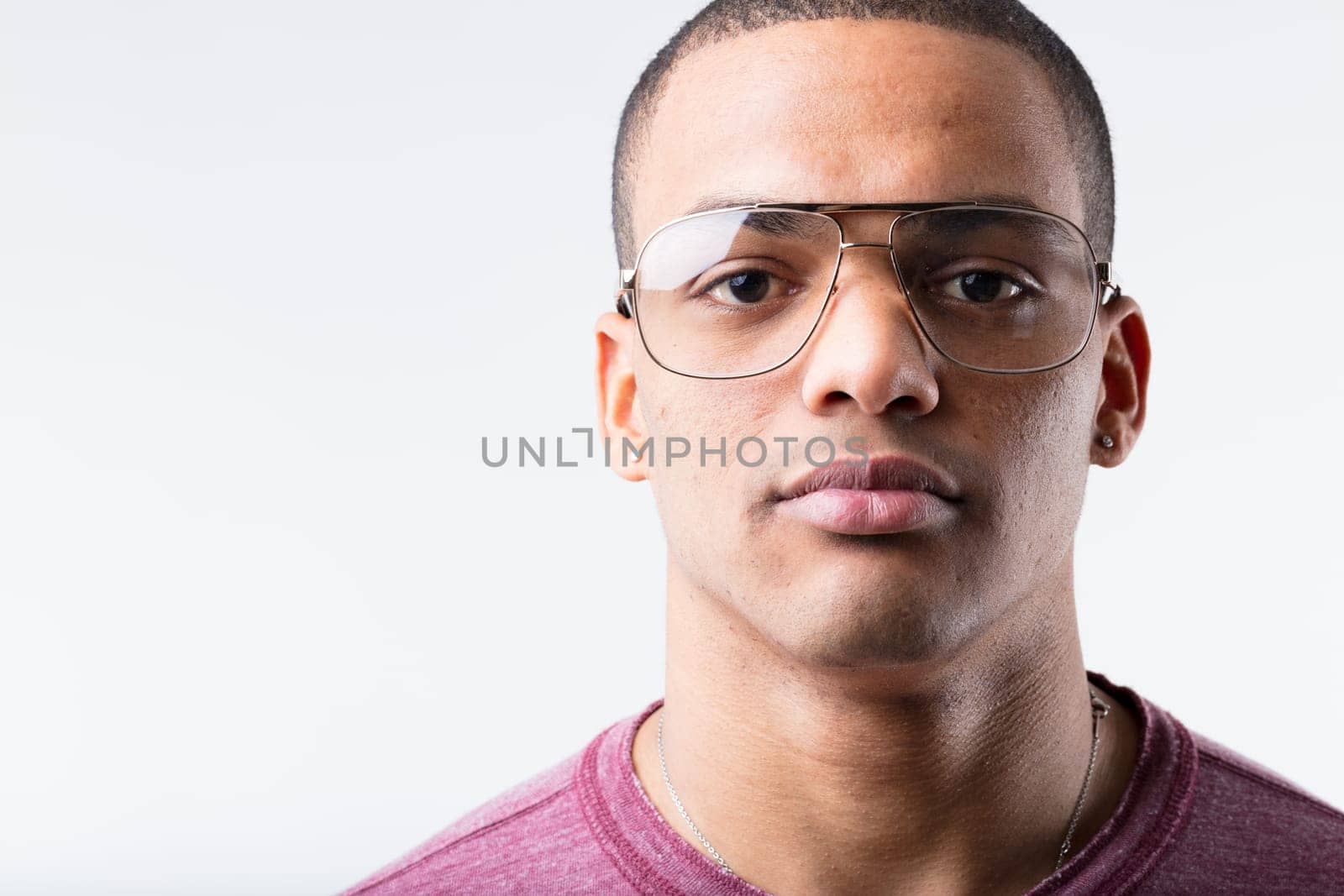 Portrait of a serious, expressionless young black man wearing metallic-framed glasses. Considered nerdy in the 80s and 90s, now they're cool. Fashion is strange