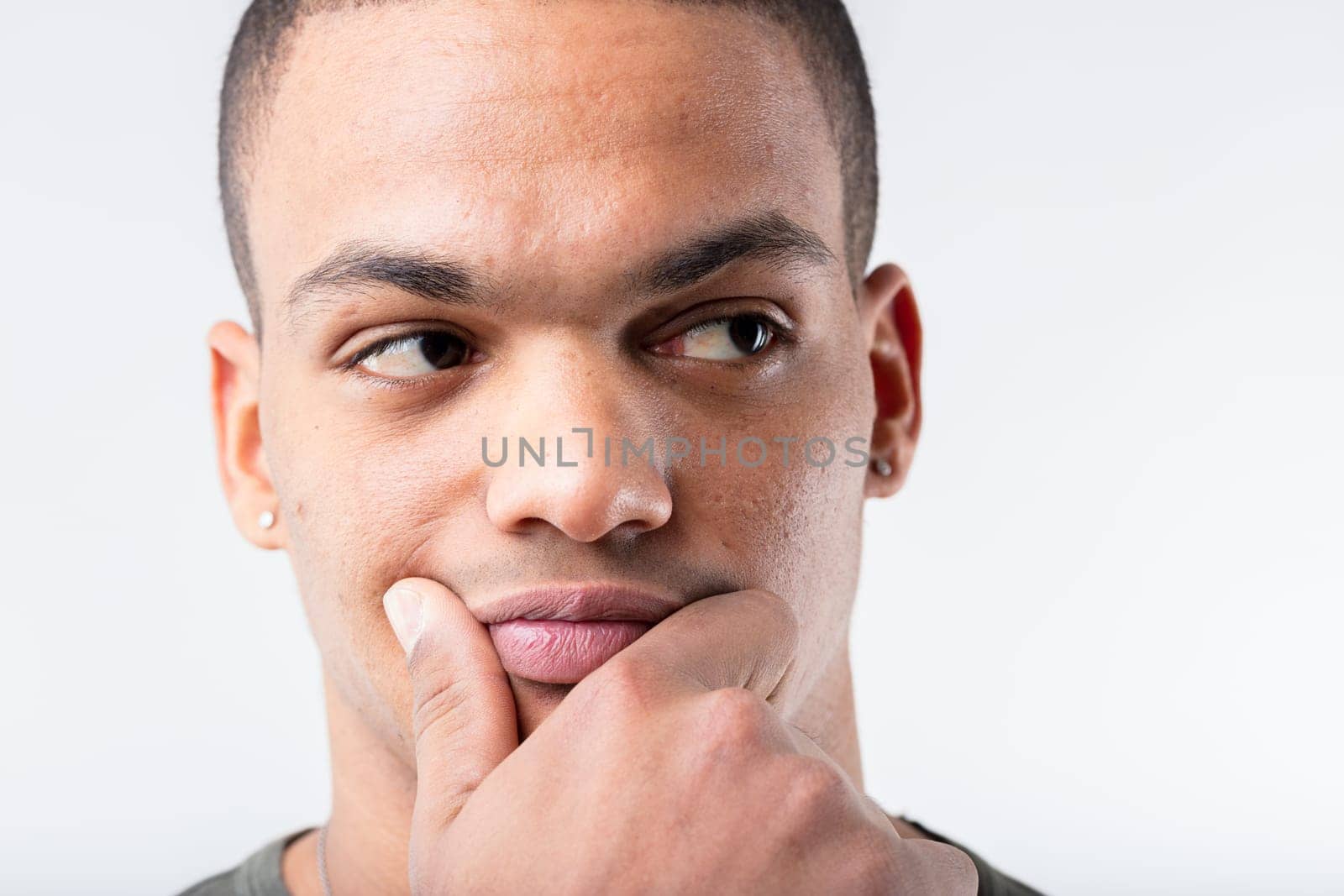 Close-up of a black man thinking hard. He could have a brilliant idea for enrichment, or suspect a scam, all while touching his lower face