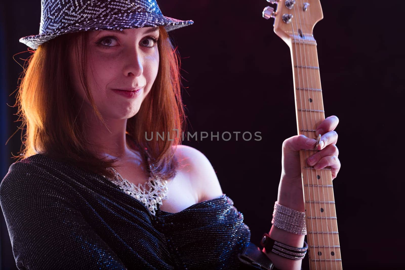 Enthusiastic red-haired guitarist in a sequined top exudes joy while engaging with her electric guitar